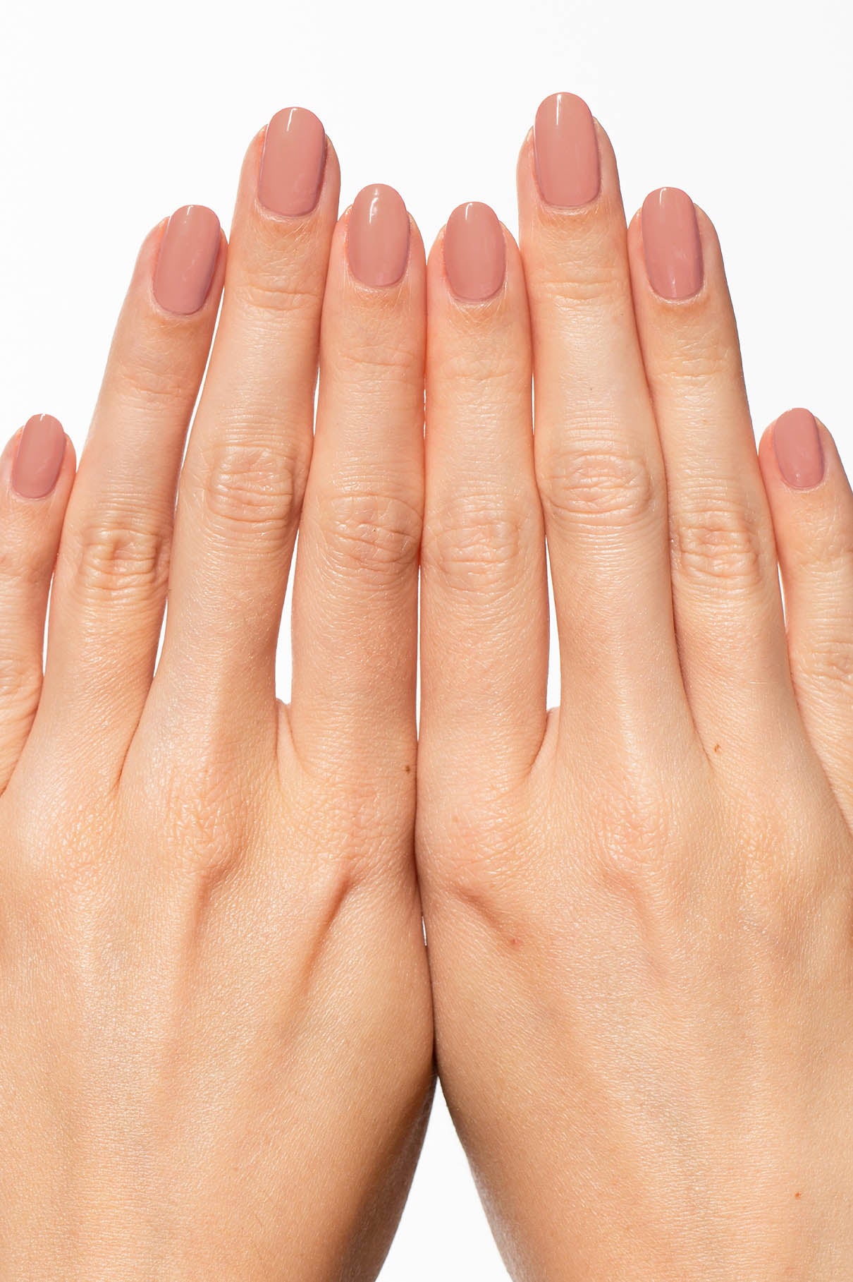 Zwei Hände mit sauber manikürten Nägeln, lackiert in gitti no. 115, einem hellen beige-rosa Farbton, sind mit ausgestreckten und sich berührenden Fingern vor einem weißen Hintergrund dargestellt.