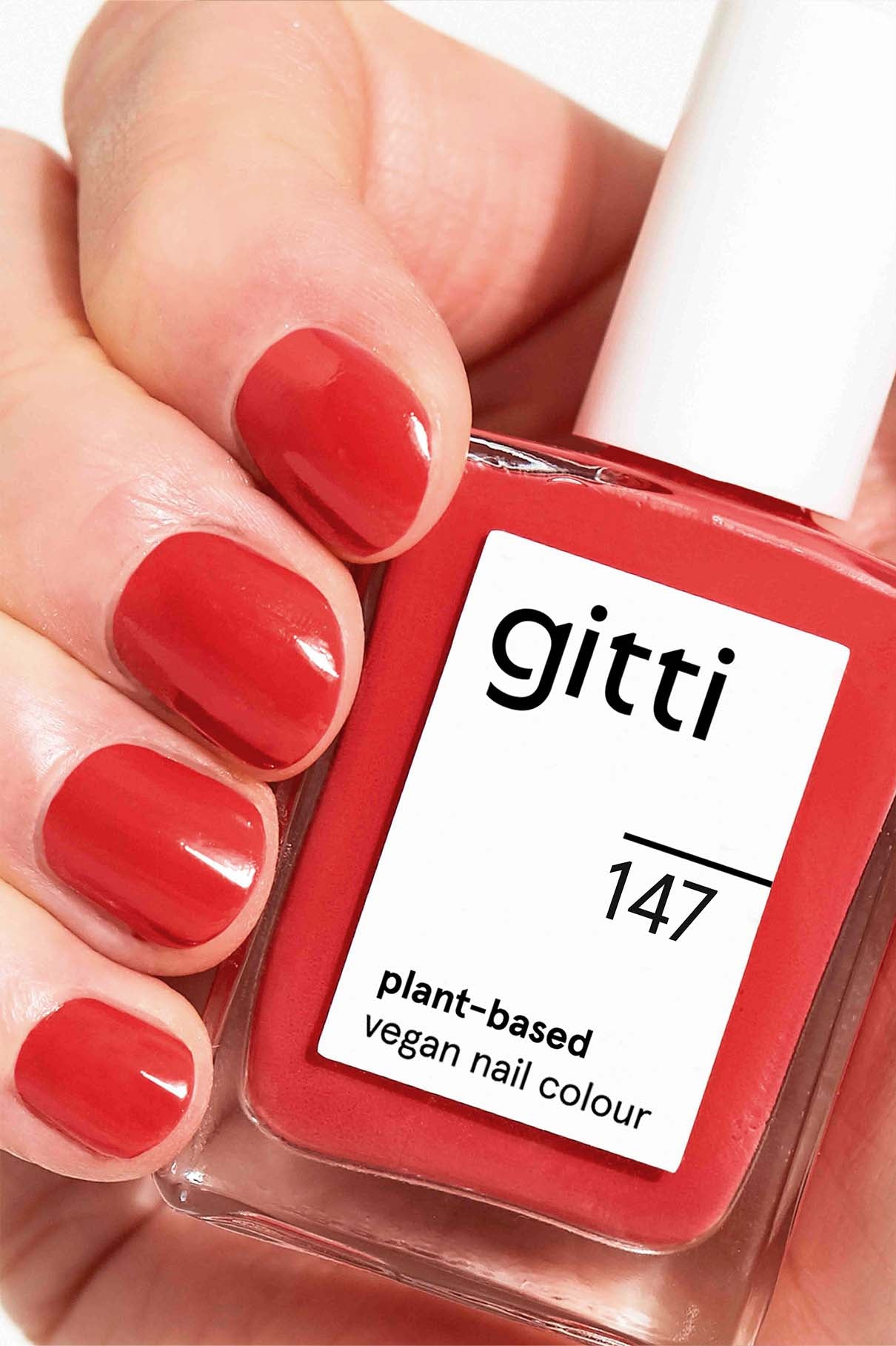 Eine Hand mit vier rot lackierten Nägeln hält ein Fläschchen aus dem gitti Express All-in-One Set in der Farbe 147, veredelt mit High Gloss Top Coat für zusätzlichen Glanz.