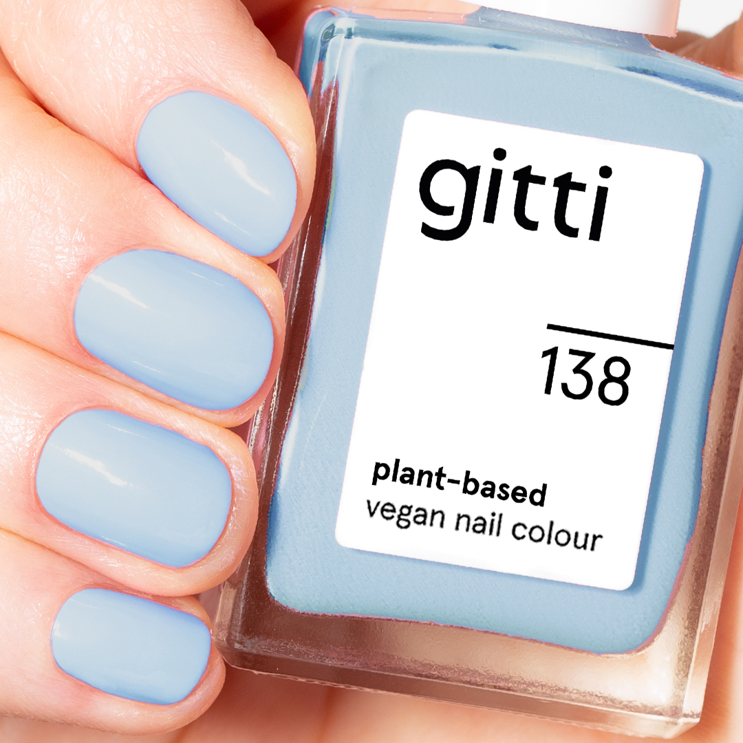 Eine Hand mit kurzen, sauber gefeilten, hellblau lackierten Nägeln hält ein Fläschchen aus dem Summer Glow Set, das pflanzliche, vegane Nagelfarbe in einem passenden Farbton enthält und mit Hydra Nail Oil frisch gepflegt wurde.