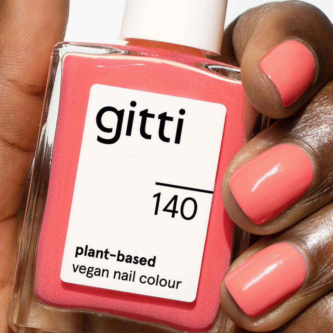 Eine Hand hält eine Flasche des pflanzlichen veganen Nagellacks gitti Summer Glow Set, die Nägel sind im gleichen rosa Farbton lackiert.