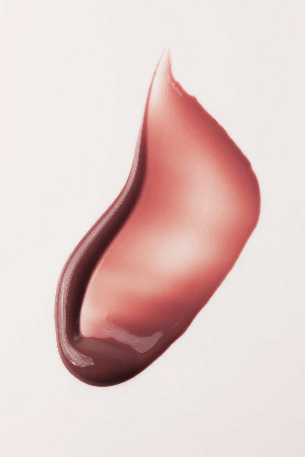 Eine Nahaufnahme eines einzelnen rosa-braunen Abstrichs von Lip Glaze no. 01 auf weißem Hintergrund, der das hochglänzende Finish hervorhebt, das für Gloss Hybrid Lippenöl-Formeln typisch ist.