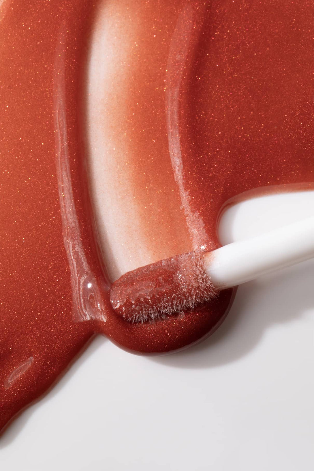 Nahaufnahme eines Make-up-Applikators auf einer weißen Fläche mit Lip Glaze no. 04 Gloss Hybrid, der für ein hochglänzendes Finish sorgt.