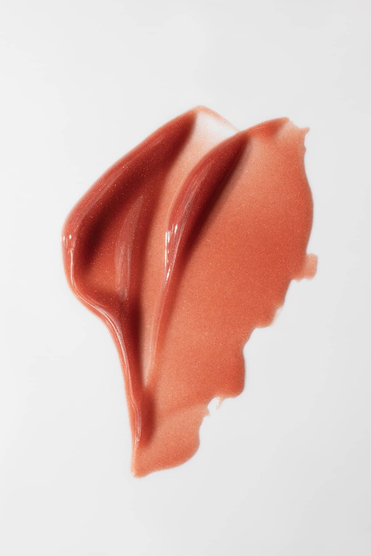 Ein Wisch mit Lip Glaze no. 04, ein schimmerndes pfirsichrosa Hybrid-Flüssig-Make-up, auf weißem Grund liefert ein hochglänzendes Finish.