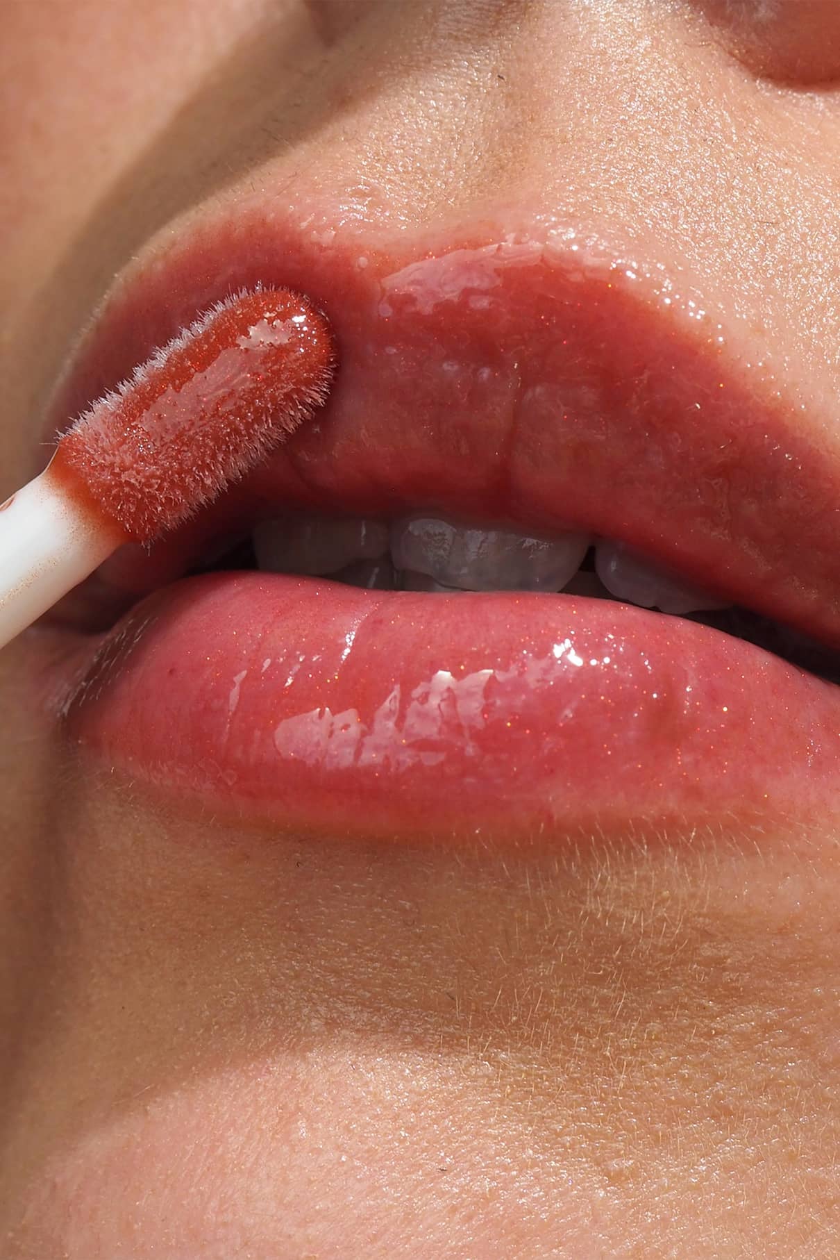 Nahaufnahme einer Person, die Lip Glaze no. 04 mit einem Applikator auf die Lippen auftragen, um ein hochglänzendes Finish zu erzielen.