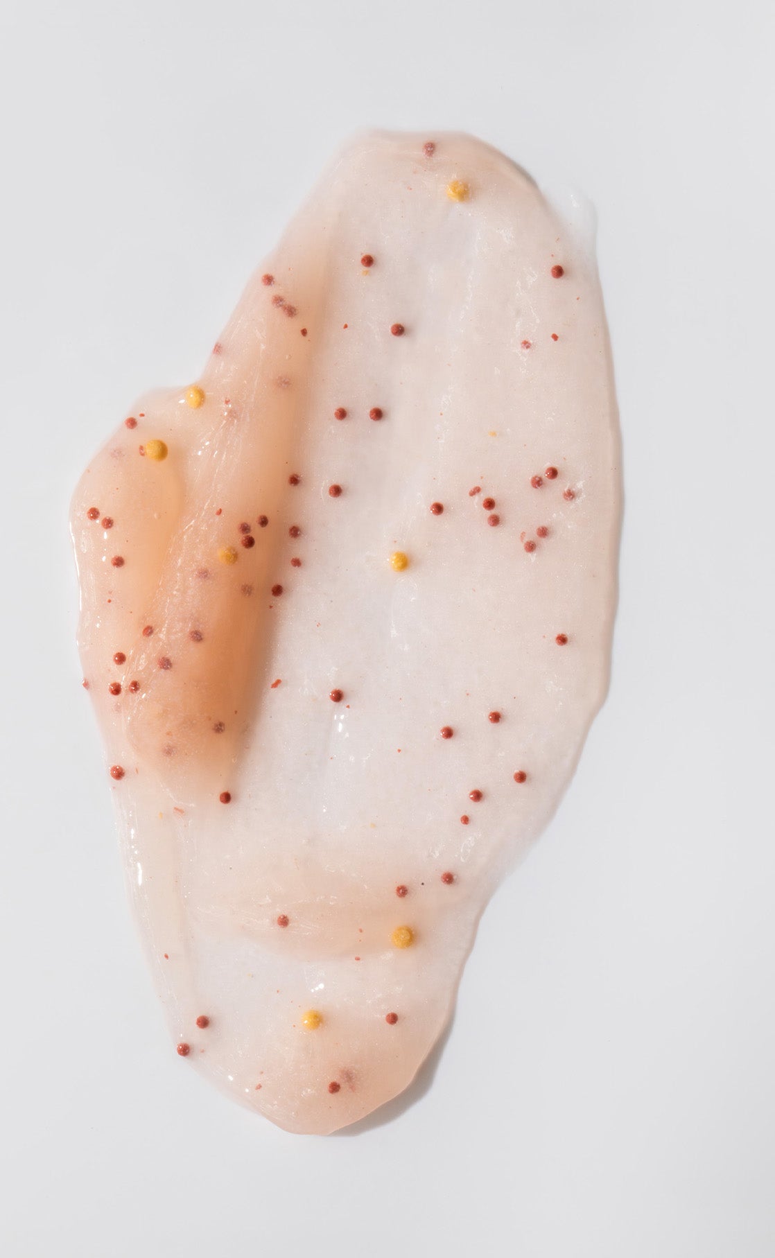 Eine durchscheinende Silky Hands Duo Creme mit kleinen roten und gelben Perlen auf weißem Grund, perfekt für Ihre Hautpflege.