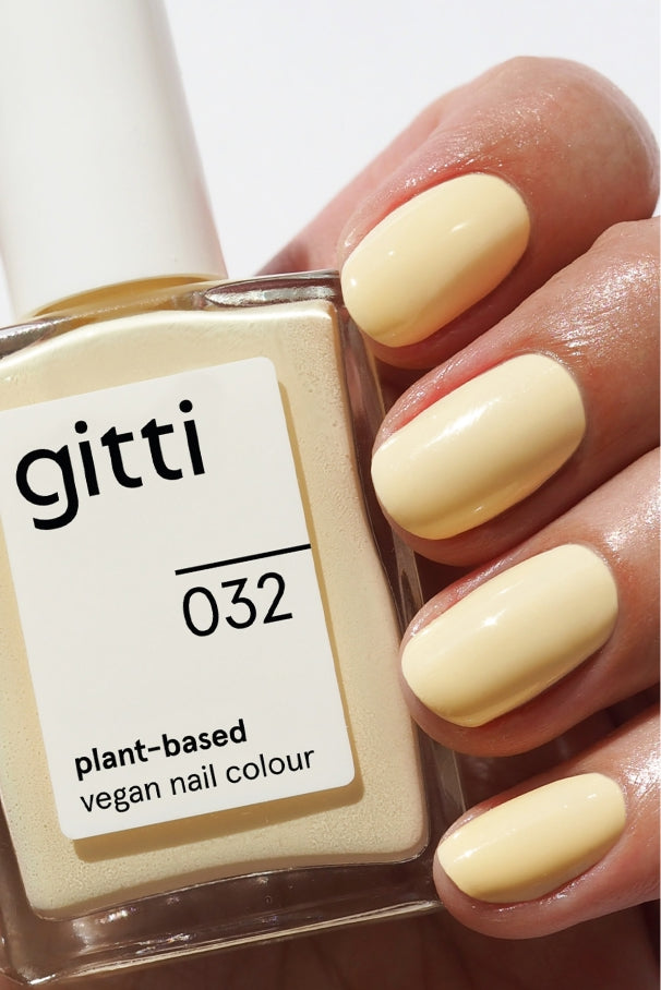 In der Hand hält gitti's Plant Duo-veganer Nagellack auf Pflanzenbasis in der Farbe 032, einem cremigen, hellen Gelb. Die Nägel passen zum Nagellack, sodass er ideal mit Set oder Top & Base Coats für ein makelloses, abgestimmtes Finish kombiniert werden kann.