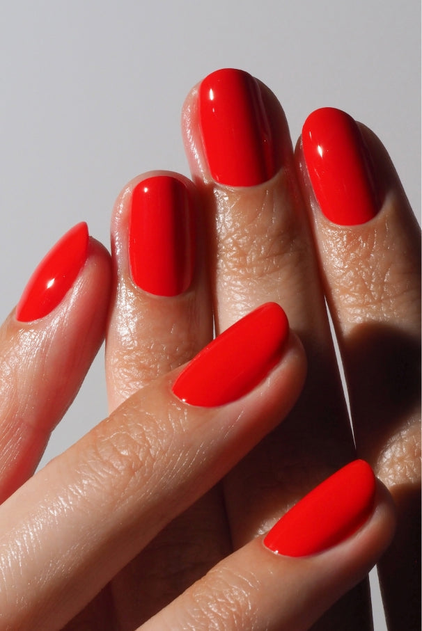 Eine Nahaufnahme einer Hand mit sauber manikürten Nägeln, die mit Plant Duo in leuchtendem Rot lackiert und mit dem Corrector Pen perfektioniert wurden.