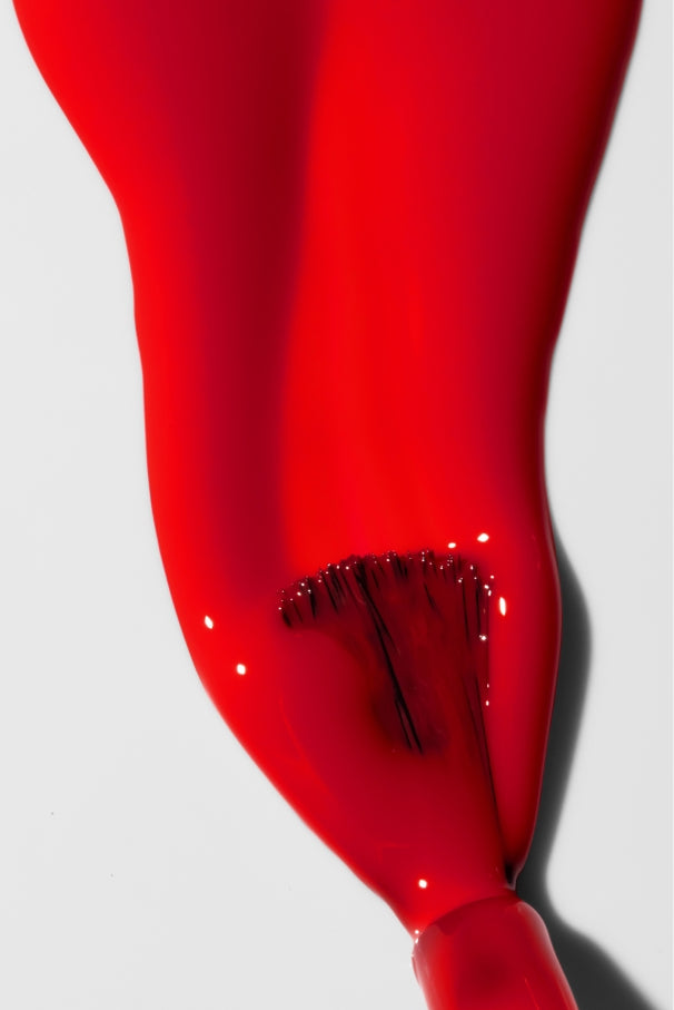 Eine Nahaufnahme von gitti no. 033 Tomatenrot Nagellack, der mit einem Pinsel auf eine weiße Fläche aufgetragen wird.