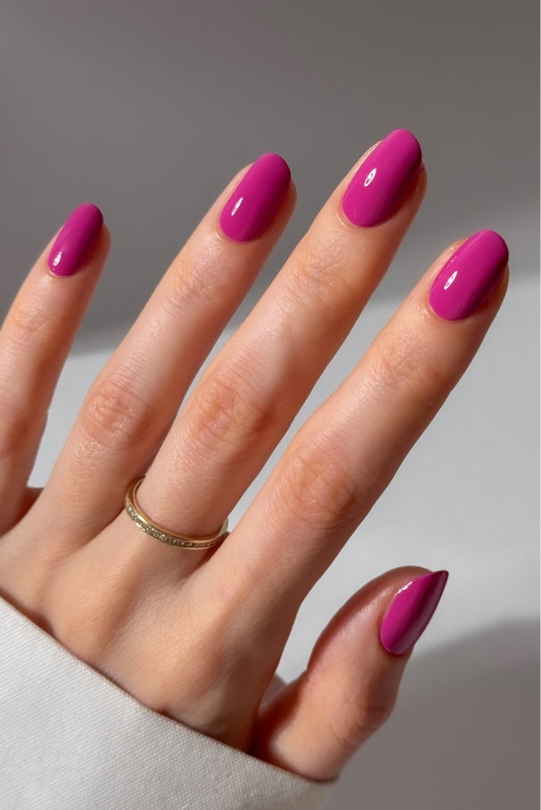 Eine Hand mit sauber manikürten Nägeln, lackiert in gitti no. 034, mit einem einfachen Goldring am Mittelfinger.