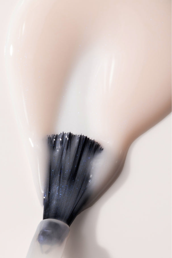 Nahaufnahme eines Pinsels, mit dem gitti no. 035, ein halbtransparenter rosafarbener Nagellack, der auf der glatten Oberfläche einen leichten Glanz hinterlässt.