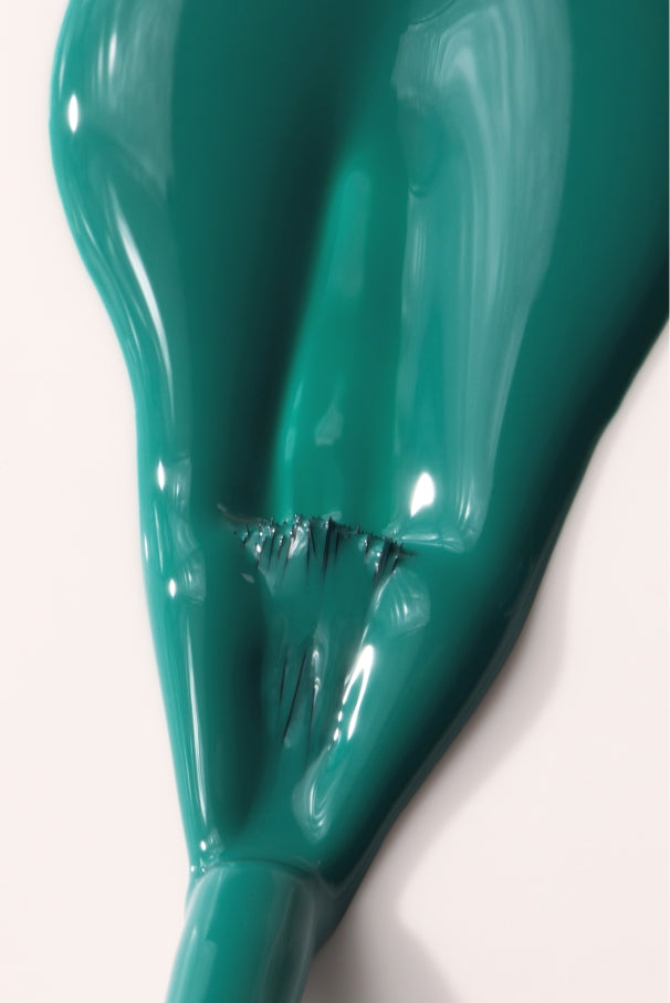 Ein teilweise entleerter und zerknitterter gitti no. 036 Ballon in einem mediterranen Grün-Blau mit schwarzen Flecken auf weißem Hintergrund.