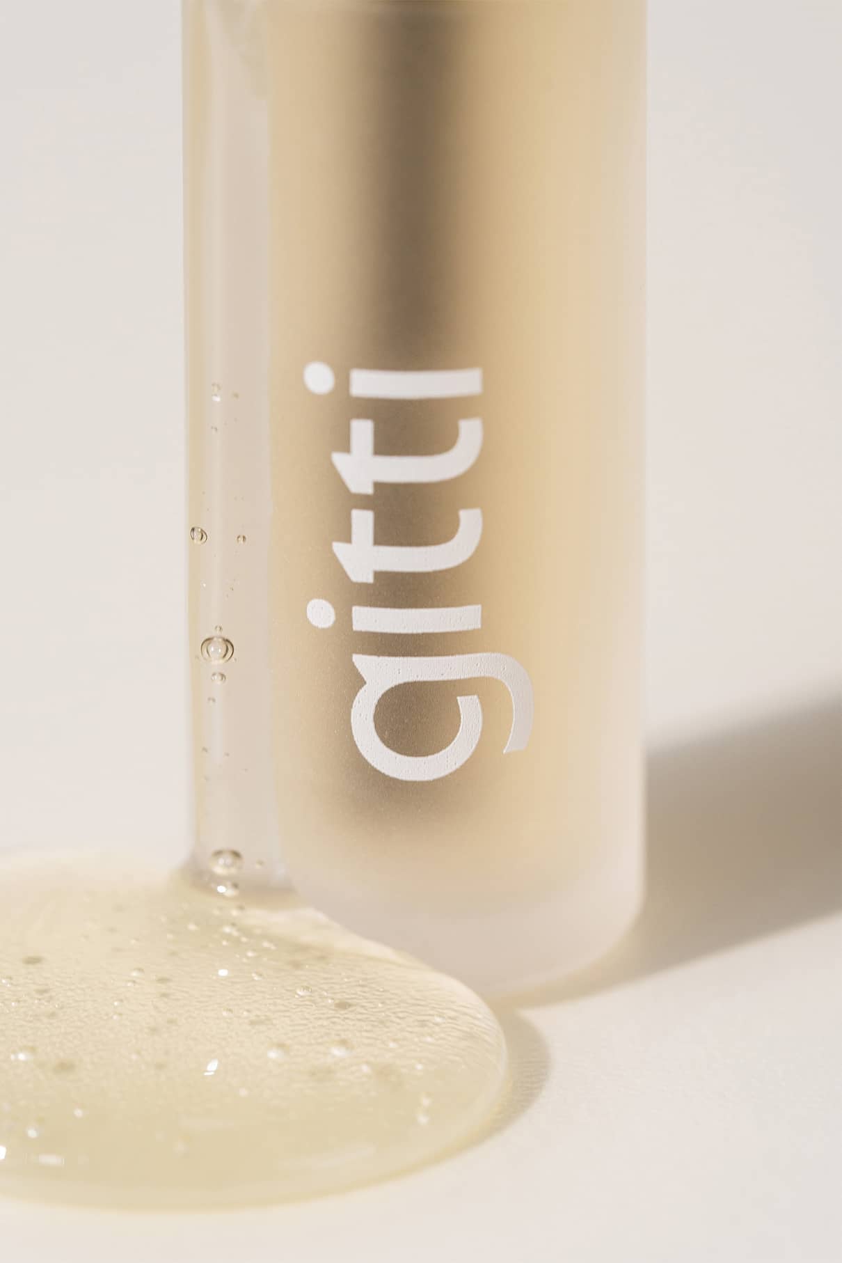 Eine klare, leichte Flüssigkeit aus einer aufrechten Flasche mit der Aufschrift Brow Control von gitti ergießt sich auf eine weiße Fläche.