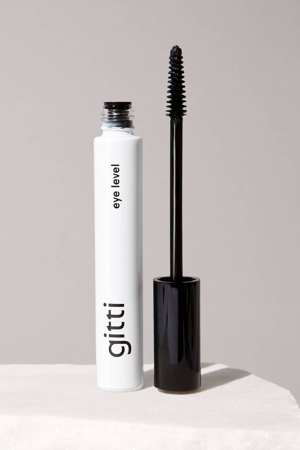 Eine Tube Eye Level Mascara von gitti, natürliches Schwarz, mit dem Applikator, der aufrecht neben der offenen Tube steht und für müheloses Volumen sorgt.