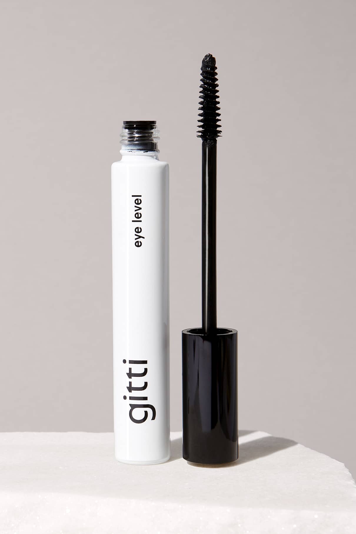 Eine Tube Eye Level Mascara von gitti, natürliches Schwarz, mit dem Applikator, der aufrecht neben der offenen Tube steht und für müheloses Volumen sorgt.