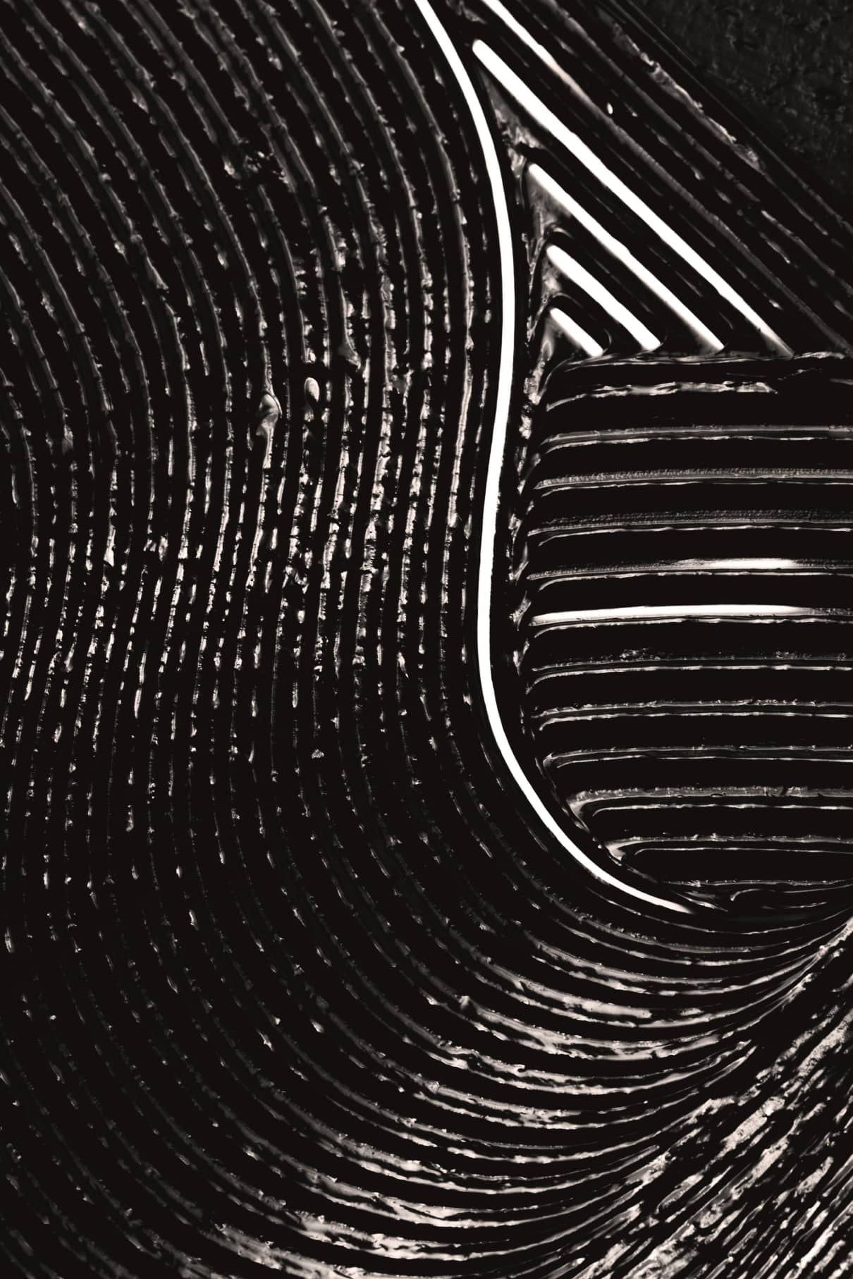 Nahaufnahme geschwungener, paralleler weißer Linien auf der dunklen demi-matten Oberfläche von Infinite Lash, die ein abstraktes geometrisches Muster mit sich kreuzenden Bögen und geraden Segmenten bilden.