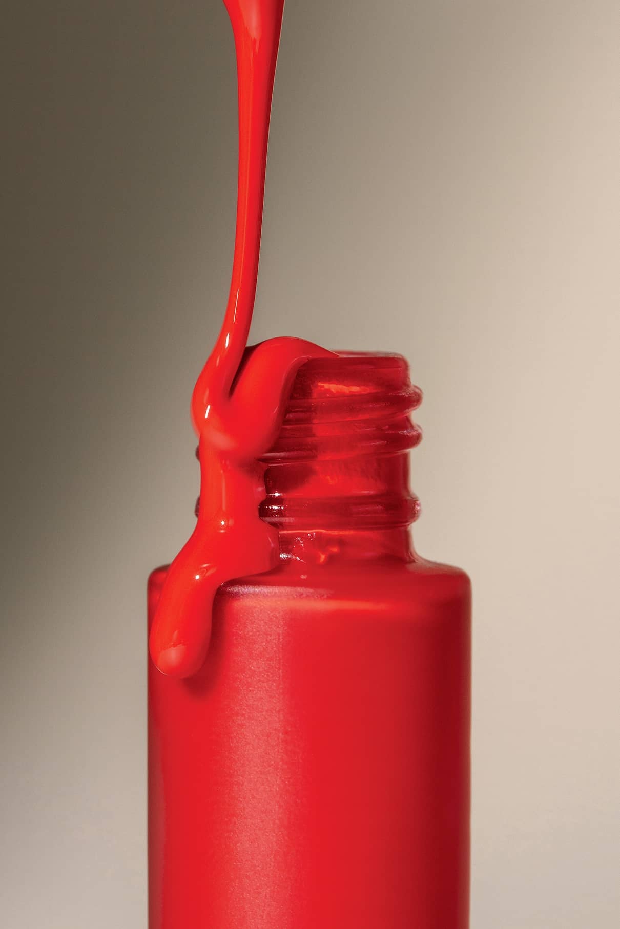 Eine Nahaufnahme der leuchtend roten Lip Glaze no. 02, der aus einer offenen Glasflasche tropft und für ein glänzendes Finish sorgt, das an Ihren Lieblingsgloss oder Ihr Lippenöl erinnert.