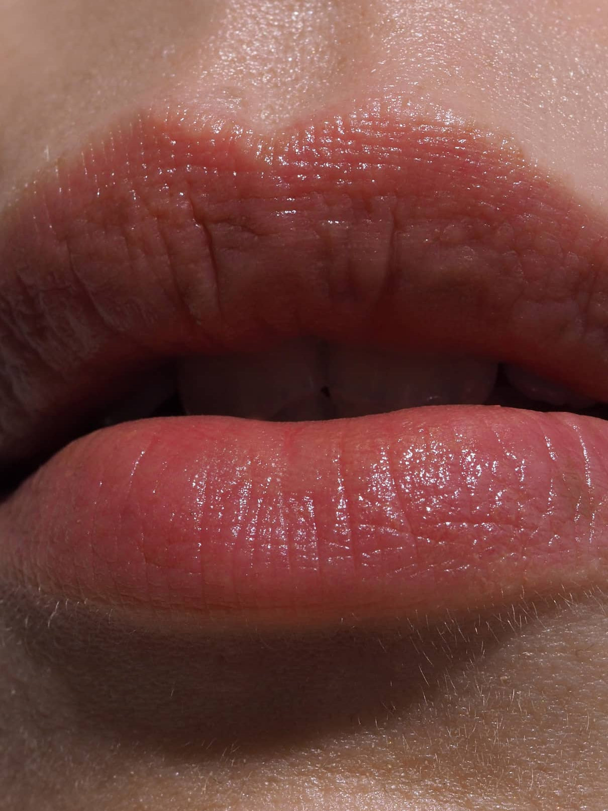 Nahaufnahme der natürlichen Lippen mit Lip Sync Refill Nr. 01, leicht gescheitelt, um warme braune Hauttöne mit rötlichem Unterton zu betonen und die natürliche Hautstruktur und feine Gesichtsbehaarung hervorzuheben.