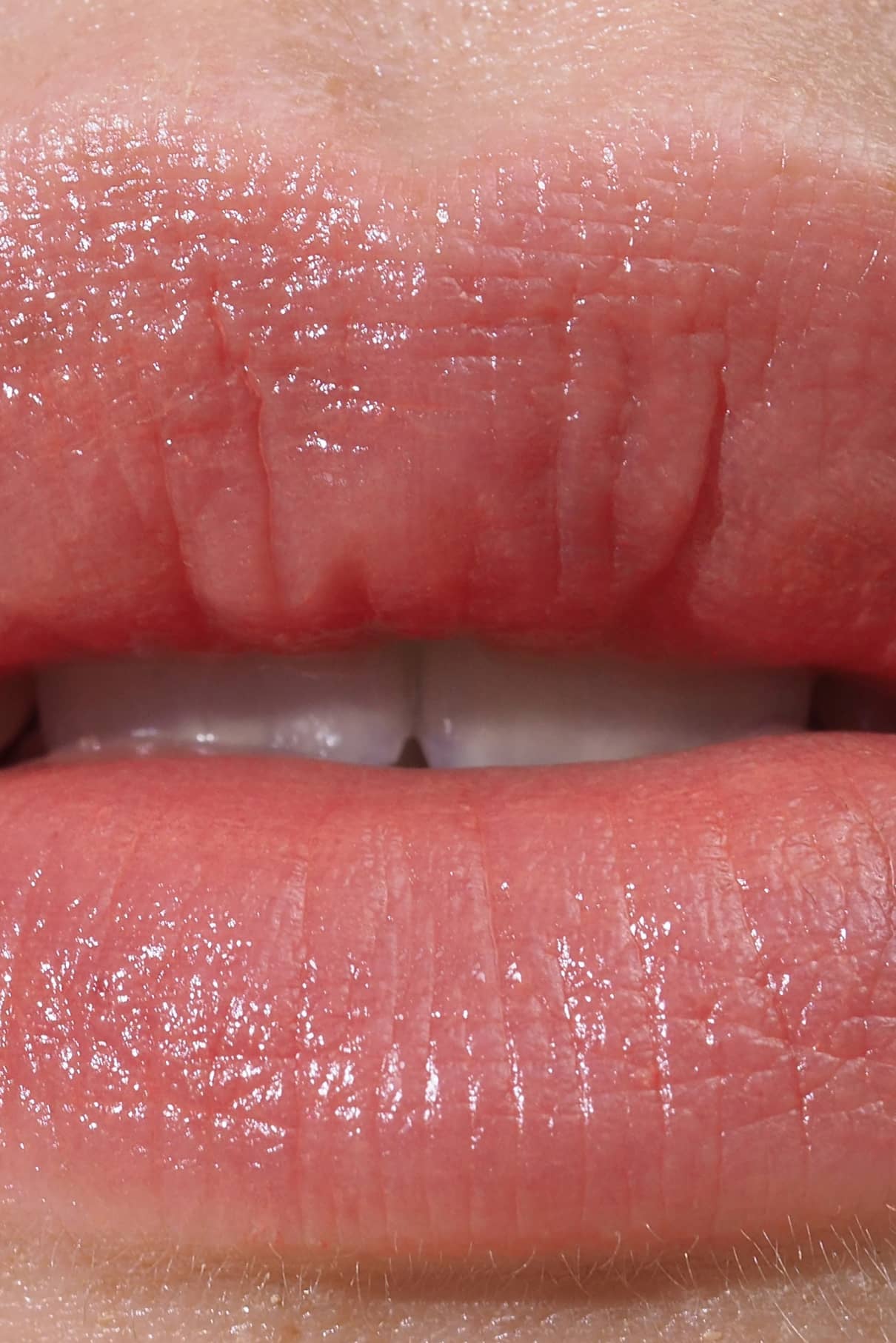 Nahaufnahme von Lippen, die Lip Sync Refill Nr. 01, mit einem natürlichen Rosaton mit rötlichem Unterton, sichtbarer Feuchtigkeit und Textur sowie einer teilweise sichtbaren oberen Zahnreihe.