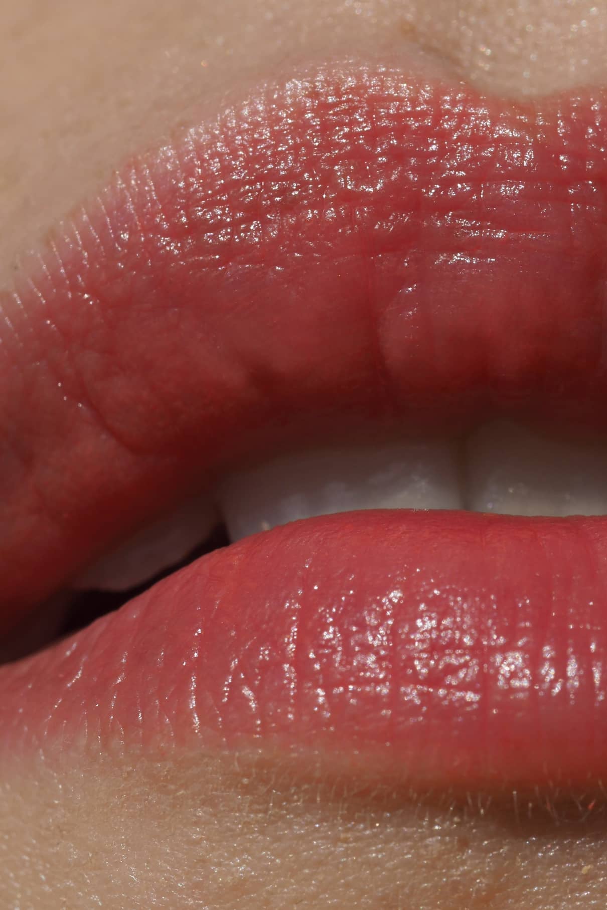 Nahaufnahme von leicht gescheitelten Lippen, die Lip Sync Refill Nr. 03, mit einem natürlichen rosa Korall-Ton und glänzender Textur - perfekt für neutrale Hauttypen.