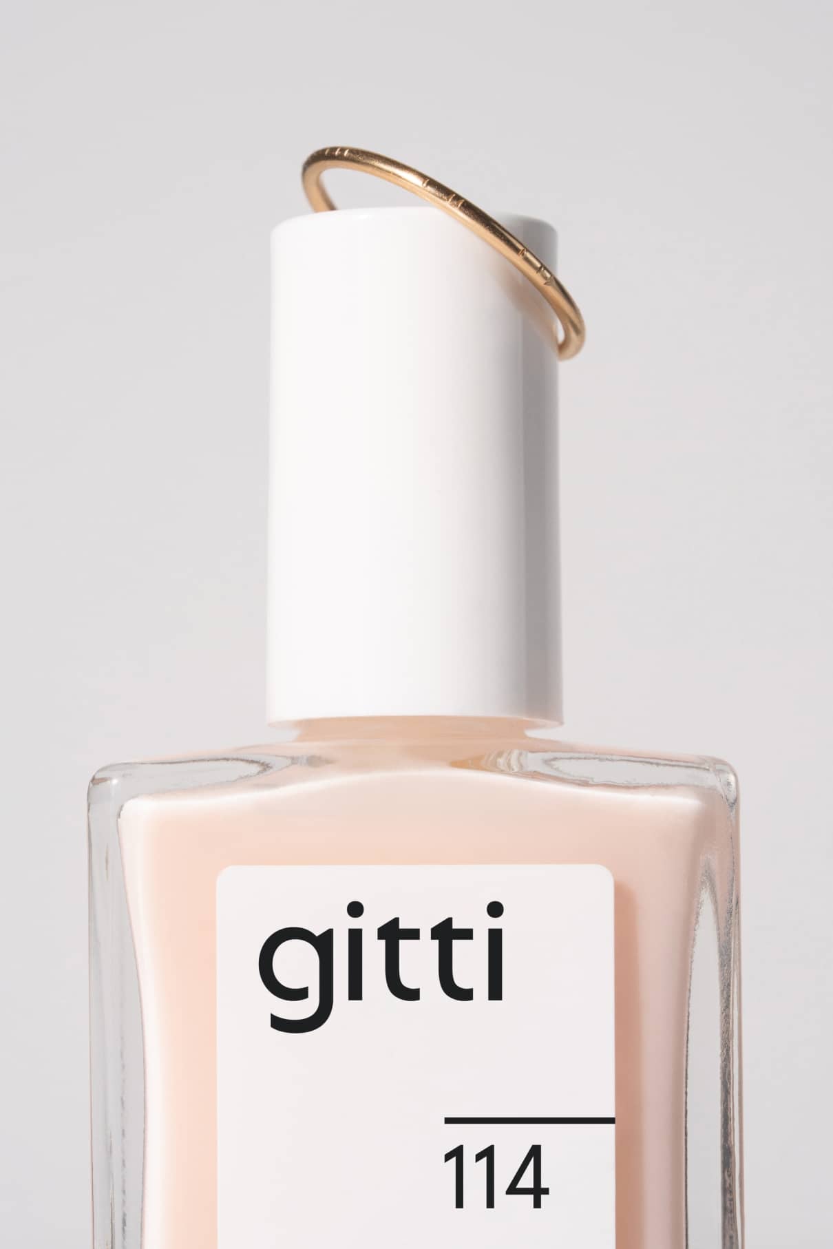Nahaufnahme einer Gitti-Nagellackflasche mit der Aufschrift 114 und dem dünnen Makaro-Pontey-Ring auf der weißen Kappe.