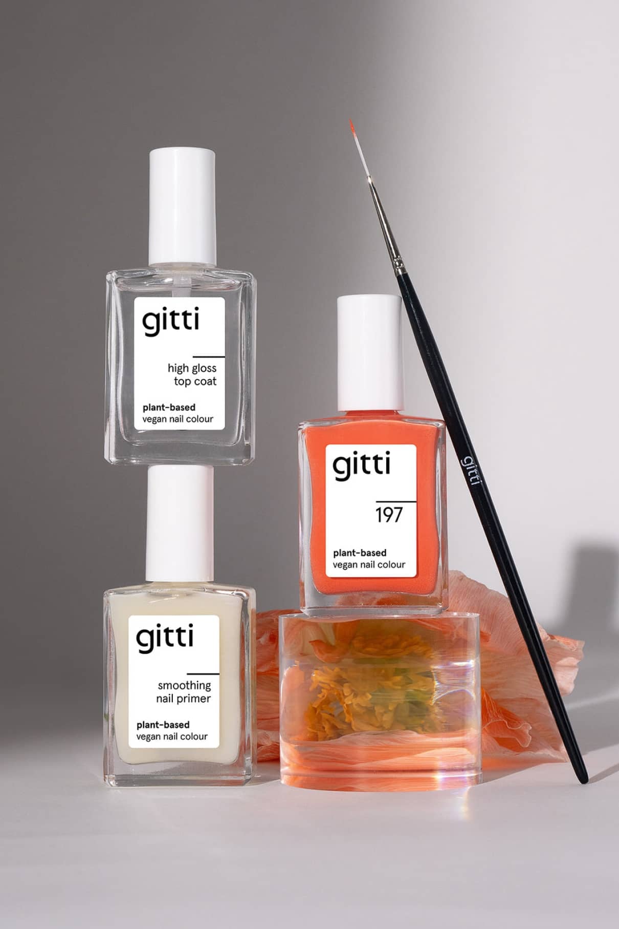 Das Nail Art Duo mit drei pflanzlichen, veganen Nagelfarben und einem Nail Art Pinsel ist mit einer orangefarbenen Blume auf hellgrauem Hintergrund versehen.