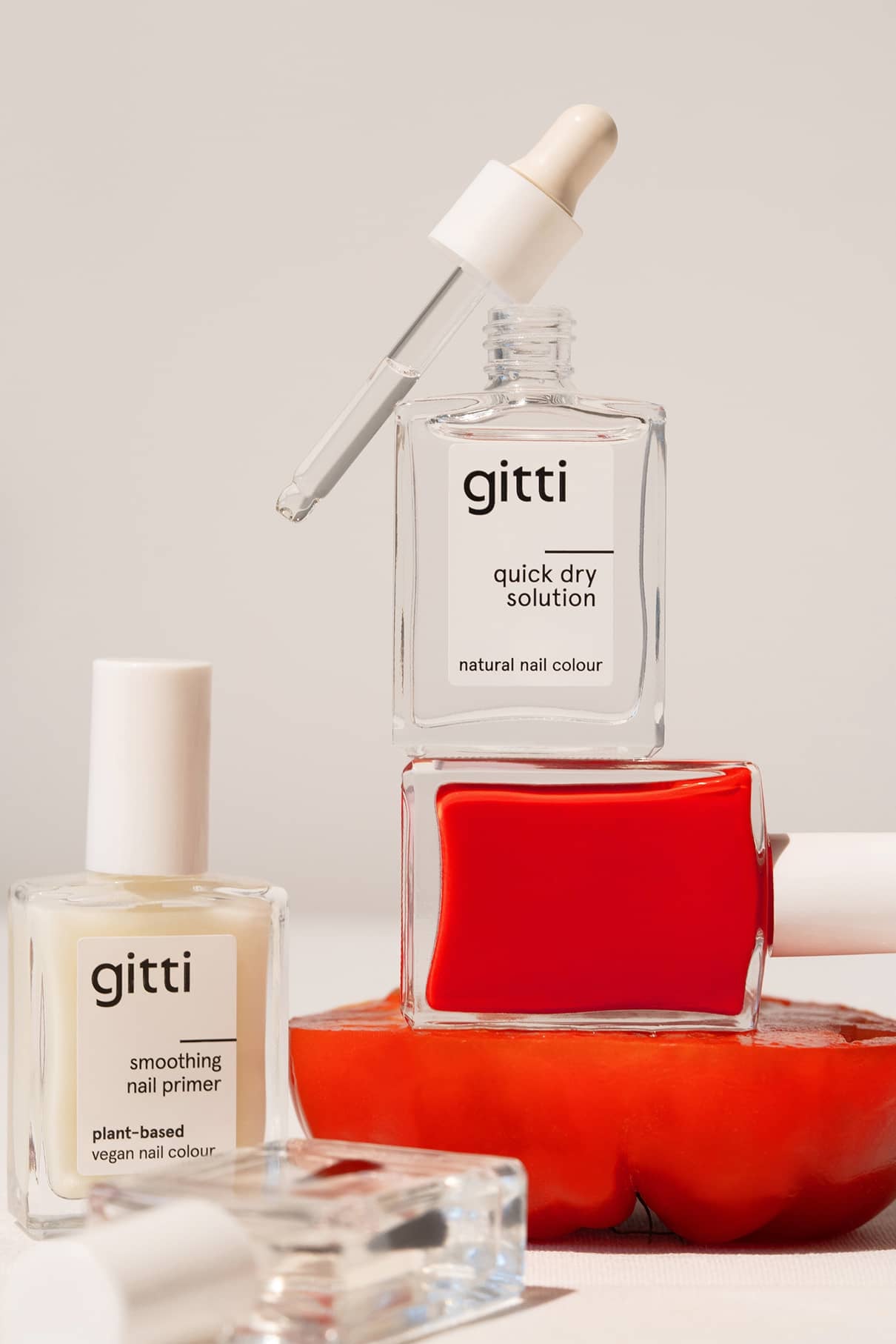 Die gitti Quick Dry Routine, bestehend aus Quick Dry Solution, Smoothing Nail Primer und rotem Lack, ist auf und um ein kühnes rotes Objekt herum gestylt, wobei ein Tropfer moderne Eleganz verleiht.