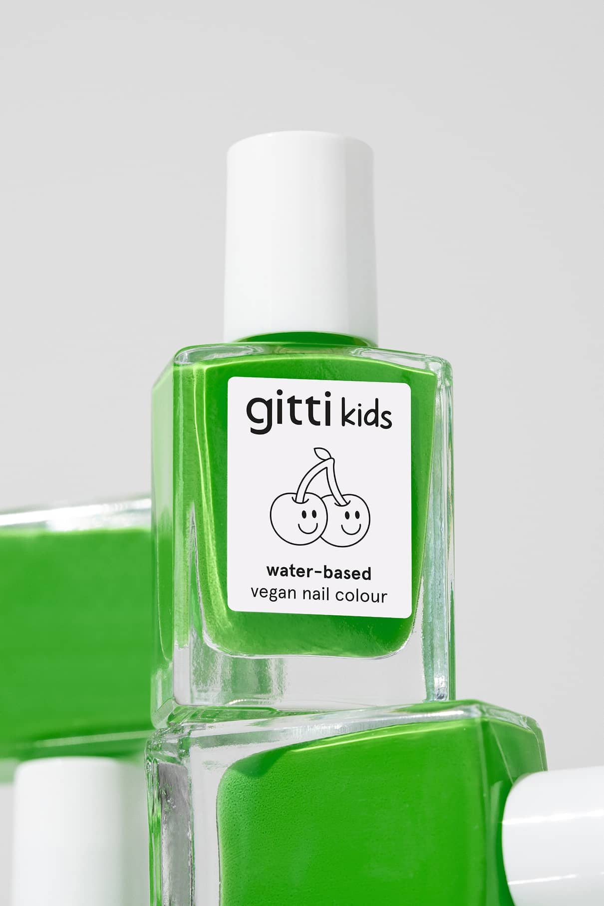 Eine Flasche gitti kids no. 04 kinderfreundliche Nagelfarbe, leuchtend grün, mit weißem Verschluss und einem Etikett mit zwei lächelnden Kirschen.