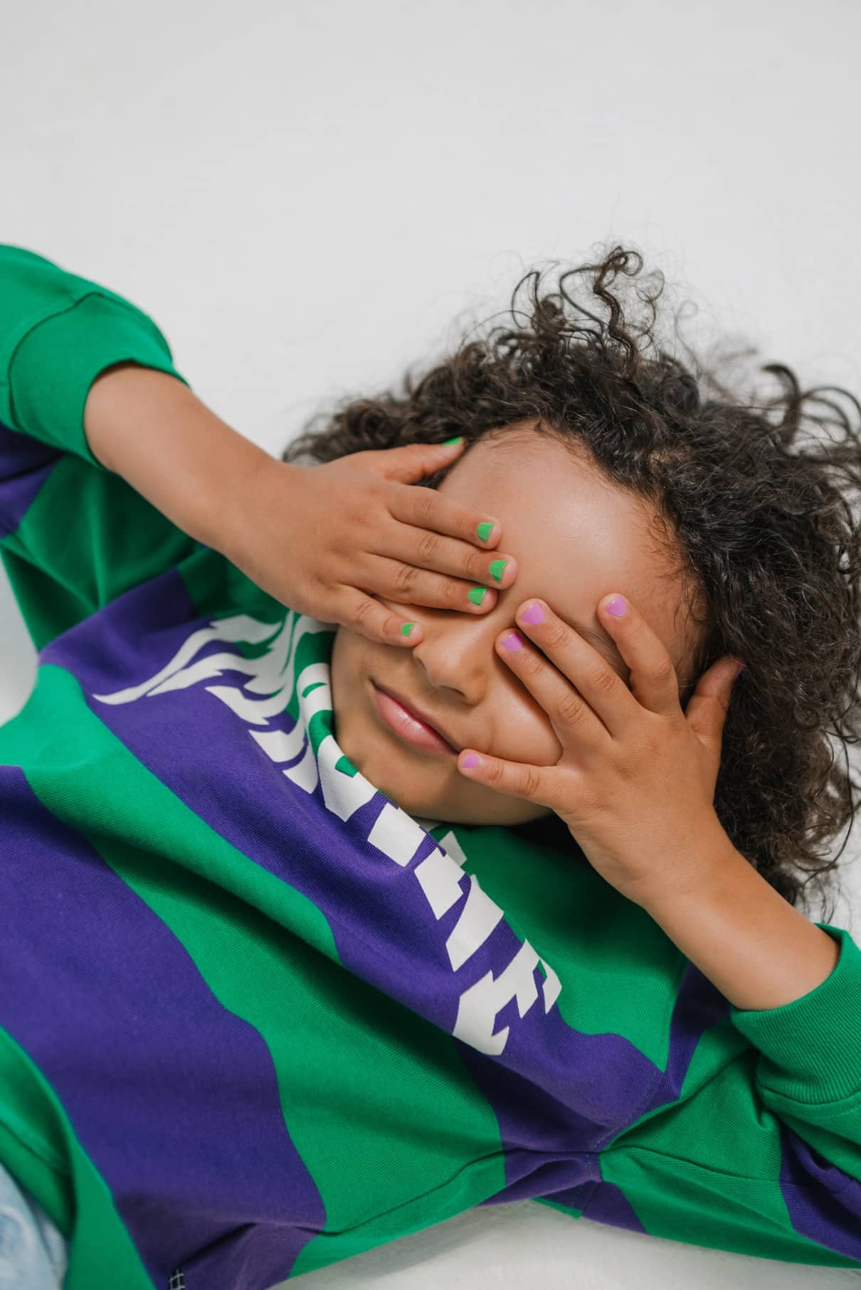 Ein Kind bedeckt seine Augen mit den Händen und zeigt die gitti kids no. 04-kinderfreundliche Nagelfarbe in hellen, verspielten Farbtönen.
