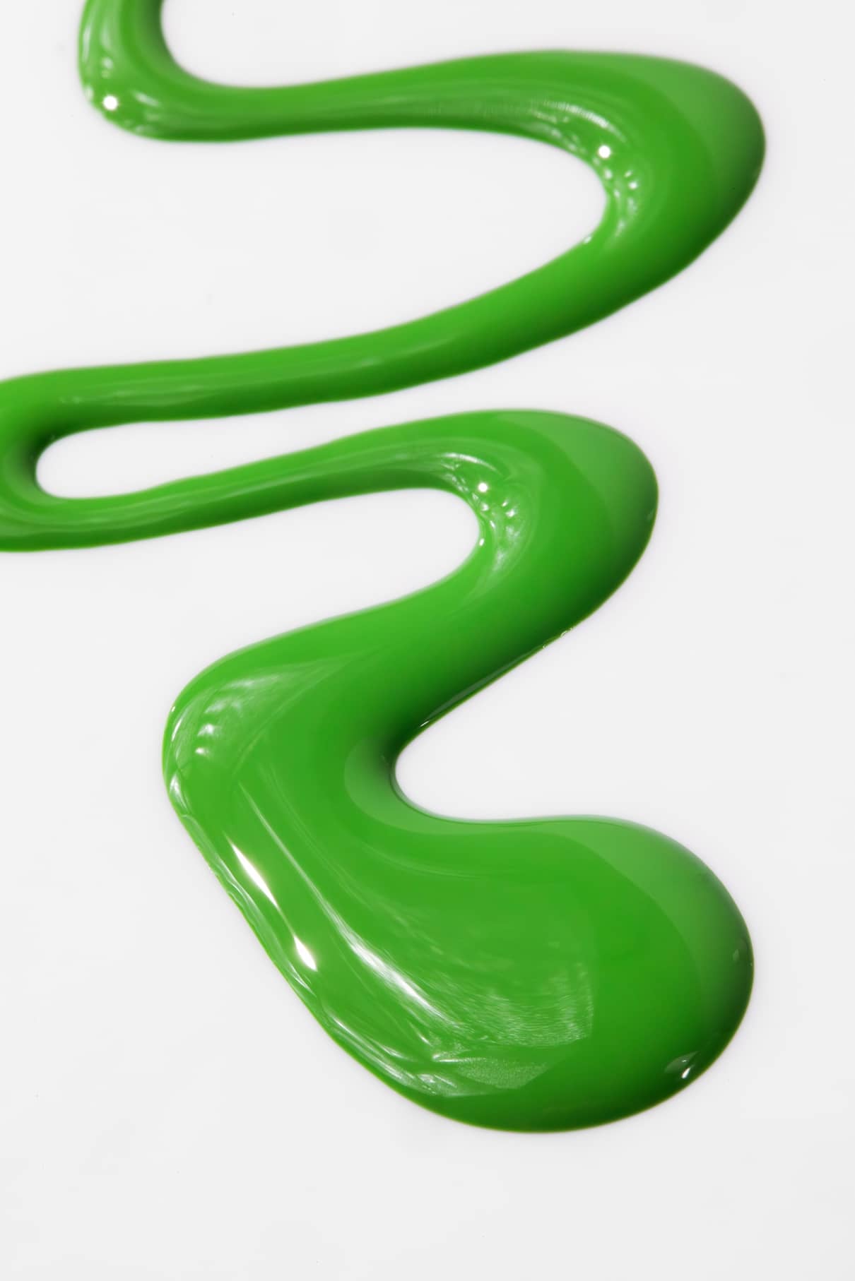 Eine Wellenlinie aus glänzend grünem gitti kids no. 04, eine kinderfreundliche Nagelfarbe, ist auf einer weißen Fläche verteilt.