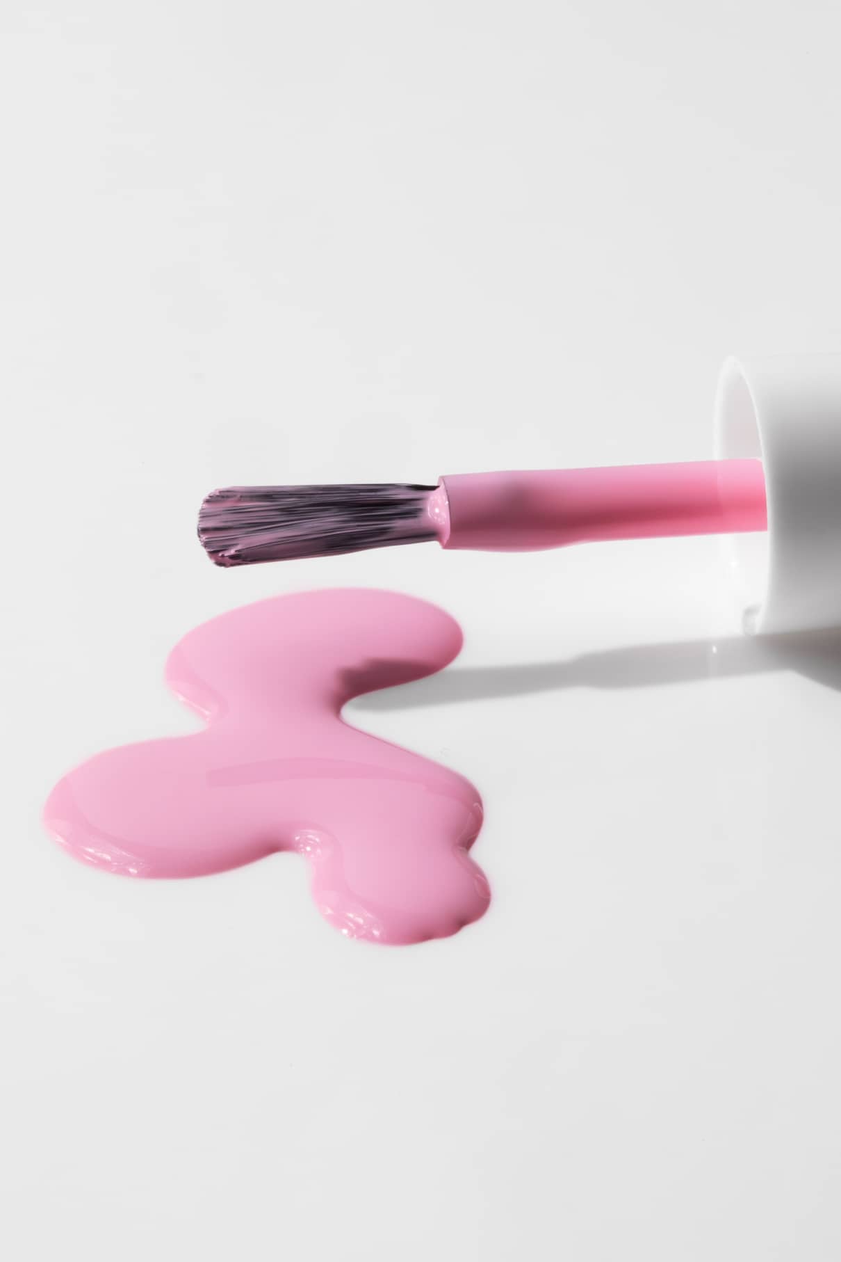 Ein Nagellackpinsel und eine Flasche gitti kids no. 05 liegen auf einer weißen Fläche, mit einem Klecks hellrosa, ungiftiger Nagellack vor ihnen.