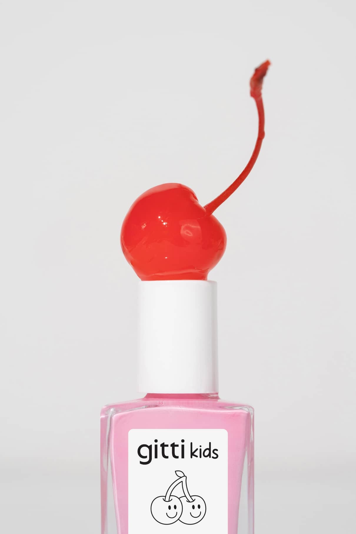 Eine Flasche rosa gitti kids no. 05 kinderfreundliche Nagelfarbe mit einer roten Kirsche auf der weißen Kappe.