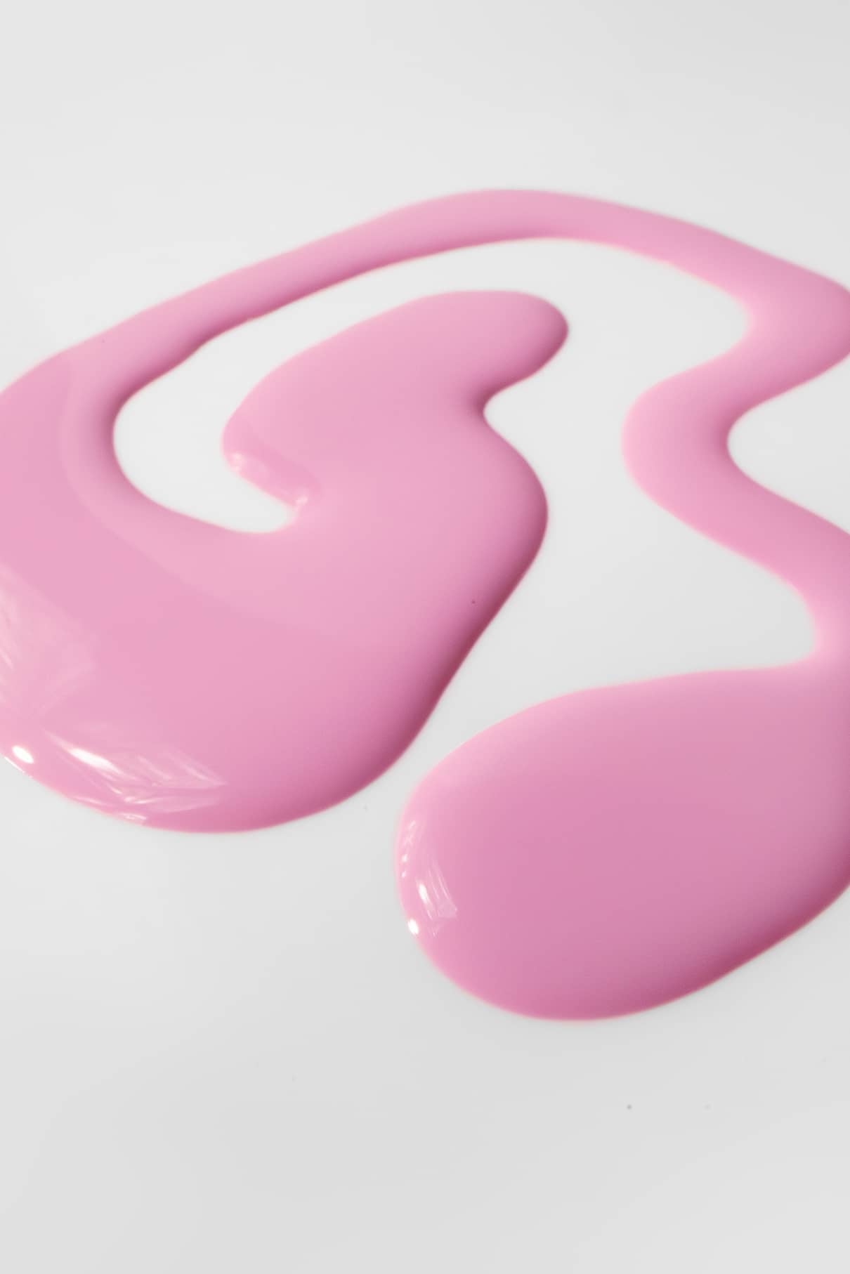 Die pinke Nagelfarbe gitti kids no. 05 ist als flüssige Farbe auf eine weiße Fläche verschüttet und bildet ein abstraktes Muster.