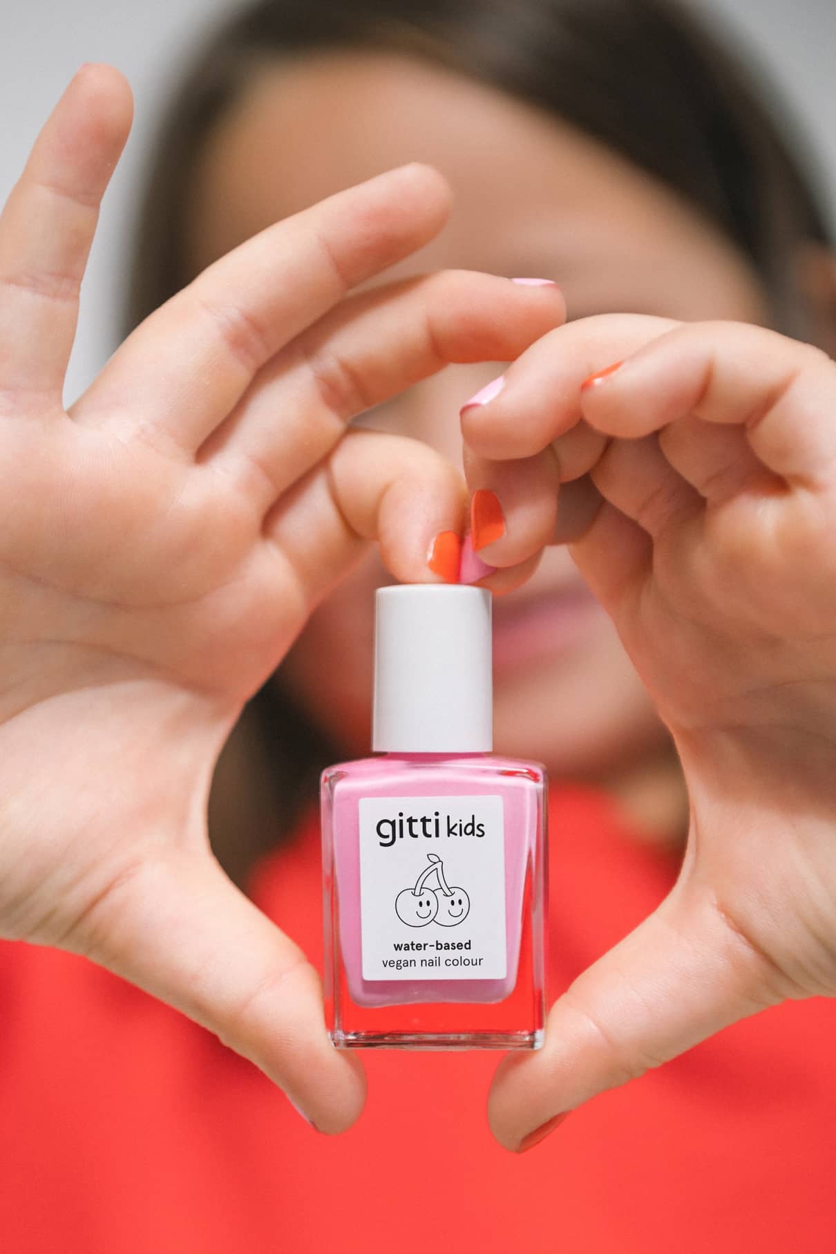 Eine Person hält eine Flasche gitti kids no. 05. Ihre Nägel sind mit dieser kinderfreundlichen Nagelfarbe in einem passenden rosa Farbton lackiert.