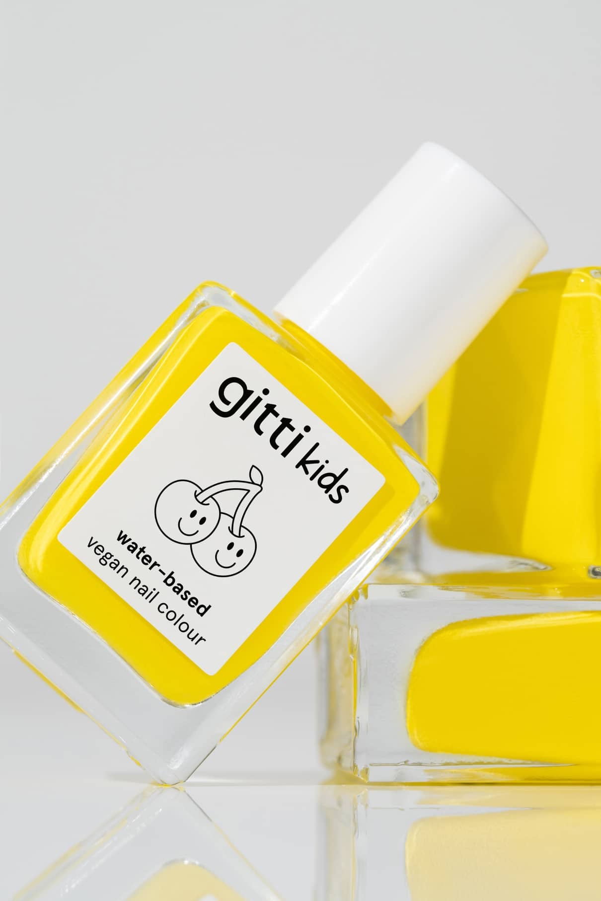 Eine Flasche mit gelbem, ungiftigem Nagellack mit der Aufschrift gitti kids no. 06, mit einer lächelnden Kirsche als Illustration - perfekt als kindgerechte Nagelfarbe.