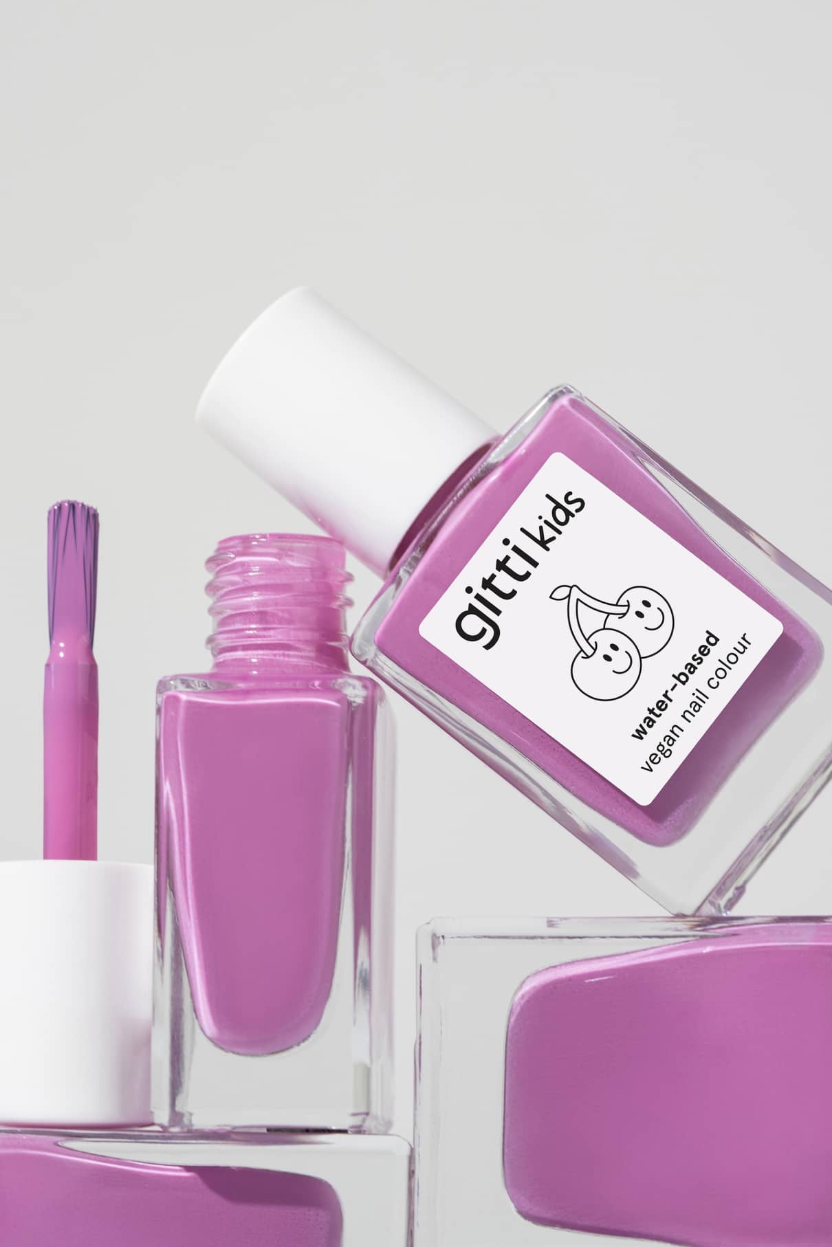Drei Flaschen gitti kids no. 07, kinderfreundliche Nagelfarbe auf Wasserbasis, mit einer geöffneten Flasche und sichtbarem Pinsel, vor einem schlichten hellen Hintergrund.