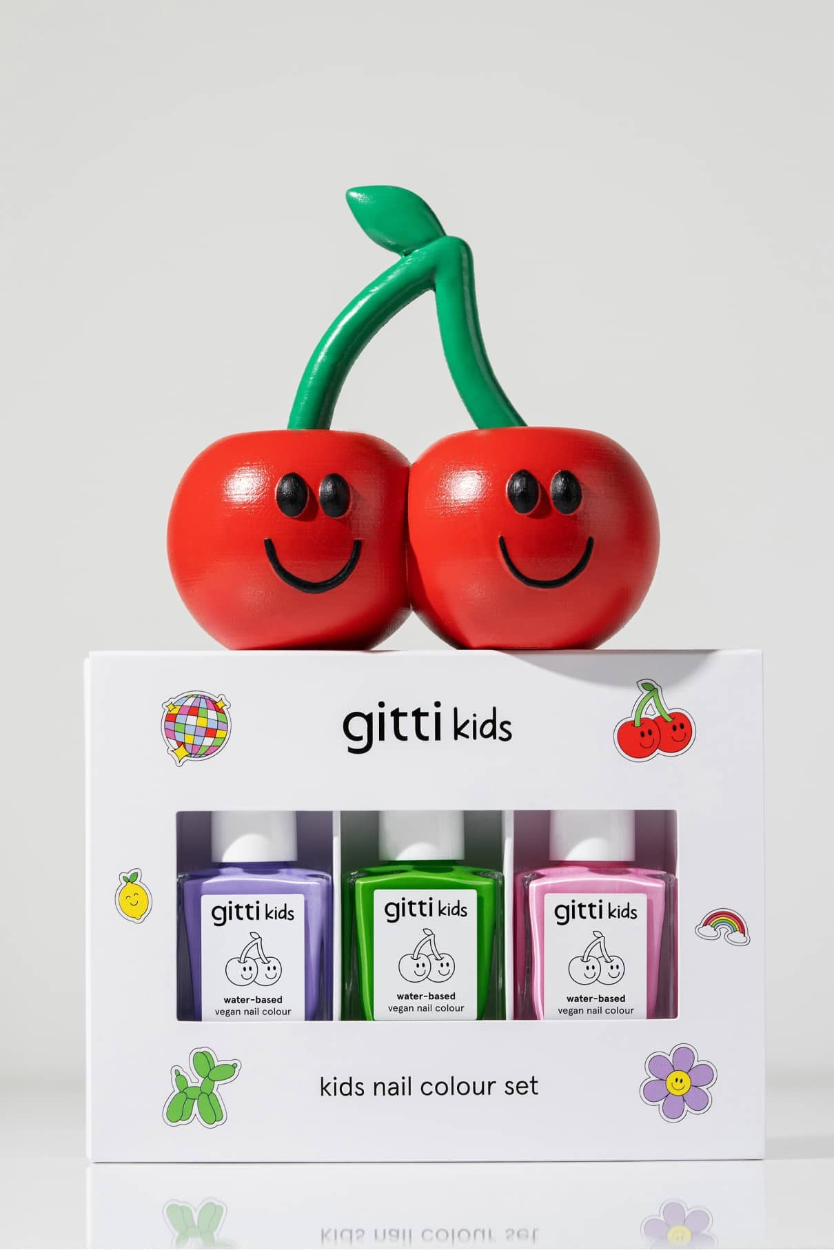 Das Little Artist Set ist ein gitti Kinder-Nagelfarben-Set mit Green Planet, La La Lilac und rosa Farbtönen, verpackt in einer weißen Schachtel mit verspielter Grafik und einer lächelnden Kirsche als Dekoration.