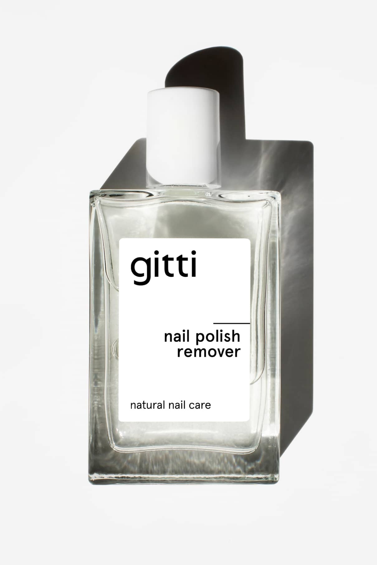 Eine Klarglasflasche Nagellackentferner mit weißem Verschluss und minimalistischem Etikett, bekannt für seinen angenehmen Duft, fotografiert auf weißem Hintergrund.