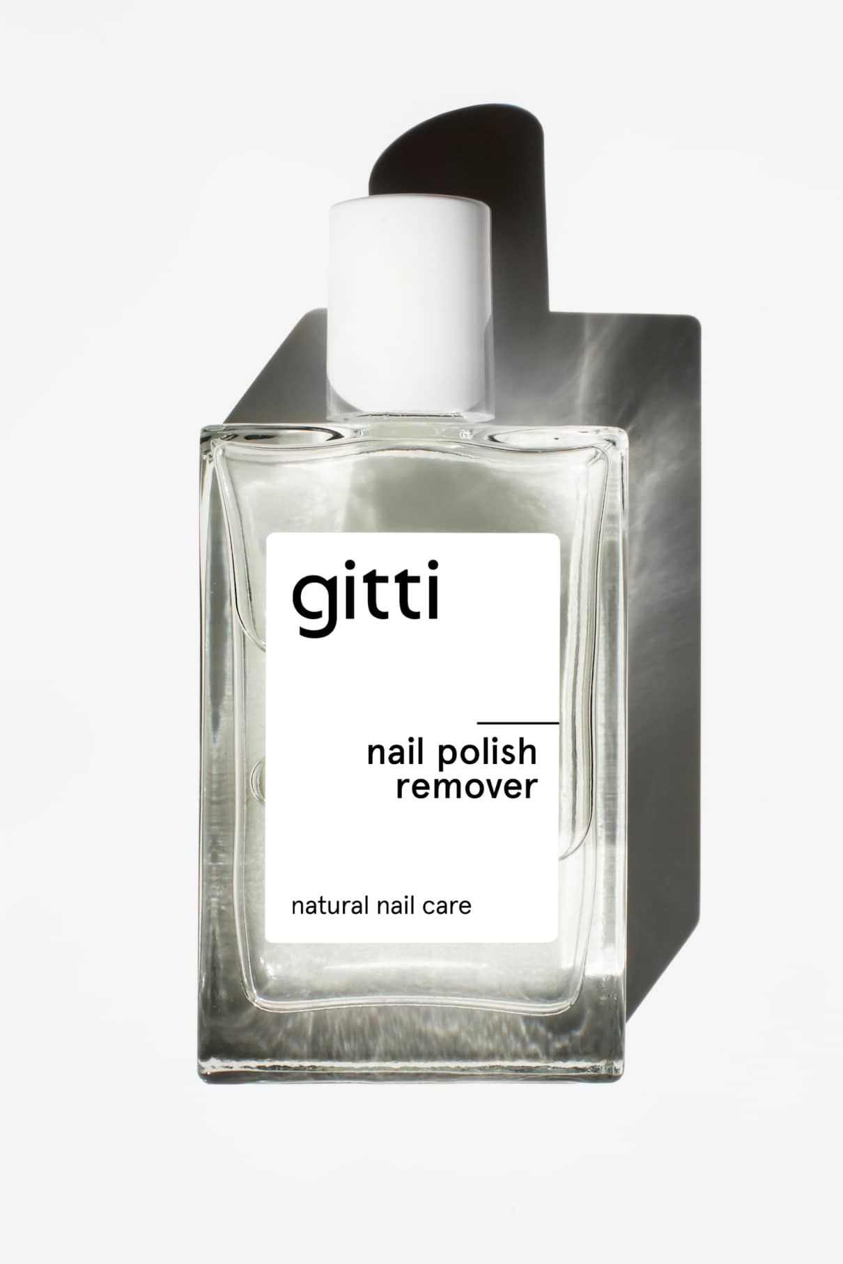 Eine Klarglasflasche Nagellackentferner mit weißem Verschluss und minimalistischem Etikett, bekannt für seinen angenehmen Duft, fotografiert auf weißem Hintergrund.
