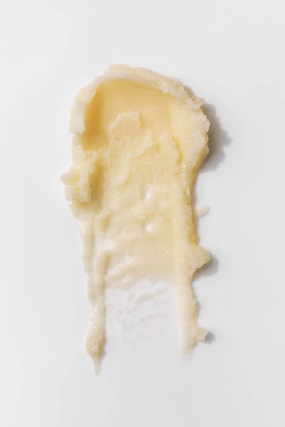 Ein Abstrich von blassgelbem Nagellackentferner-Balsam auf einer weißen Fläche.