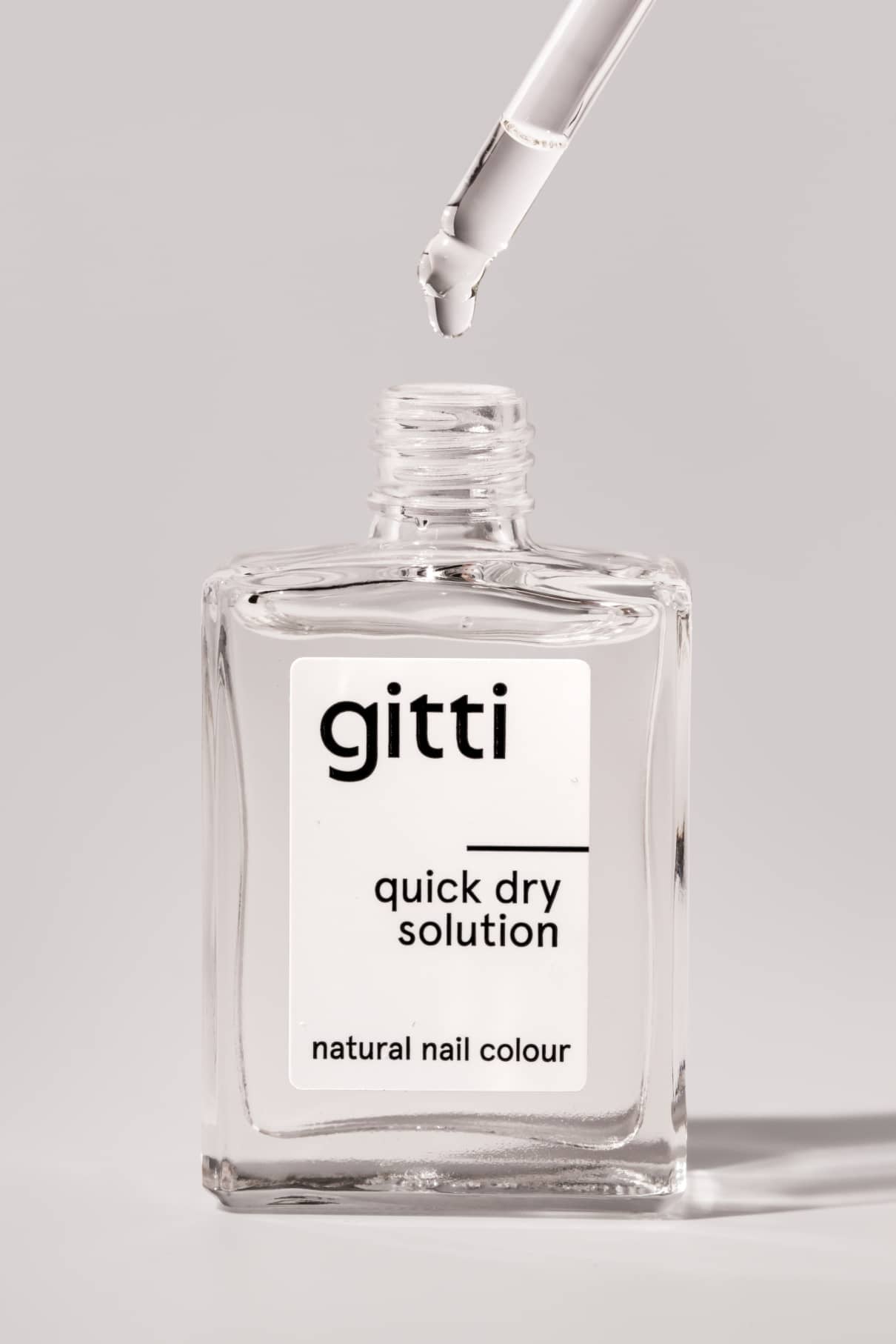 Eine klare Glasflasche mit der Aufschrift Quick Dry Solution mit offenem Deckel und einem Tropfer, der die Flüssigkeit darüber abgibt - perfekt für die schnelle Trocknung und um Ihre Nagelfarbe im Handumdrehen trocknen zu lassen.