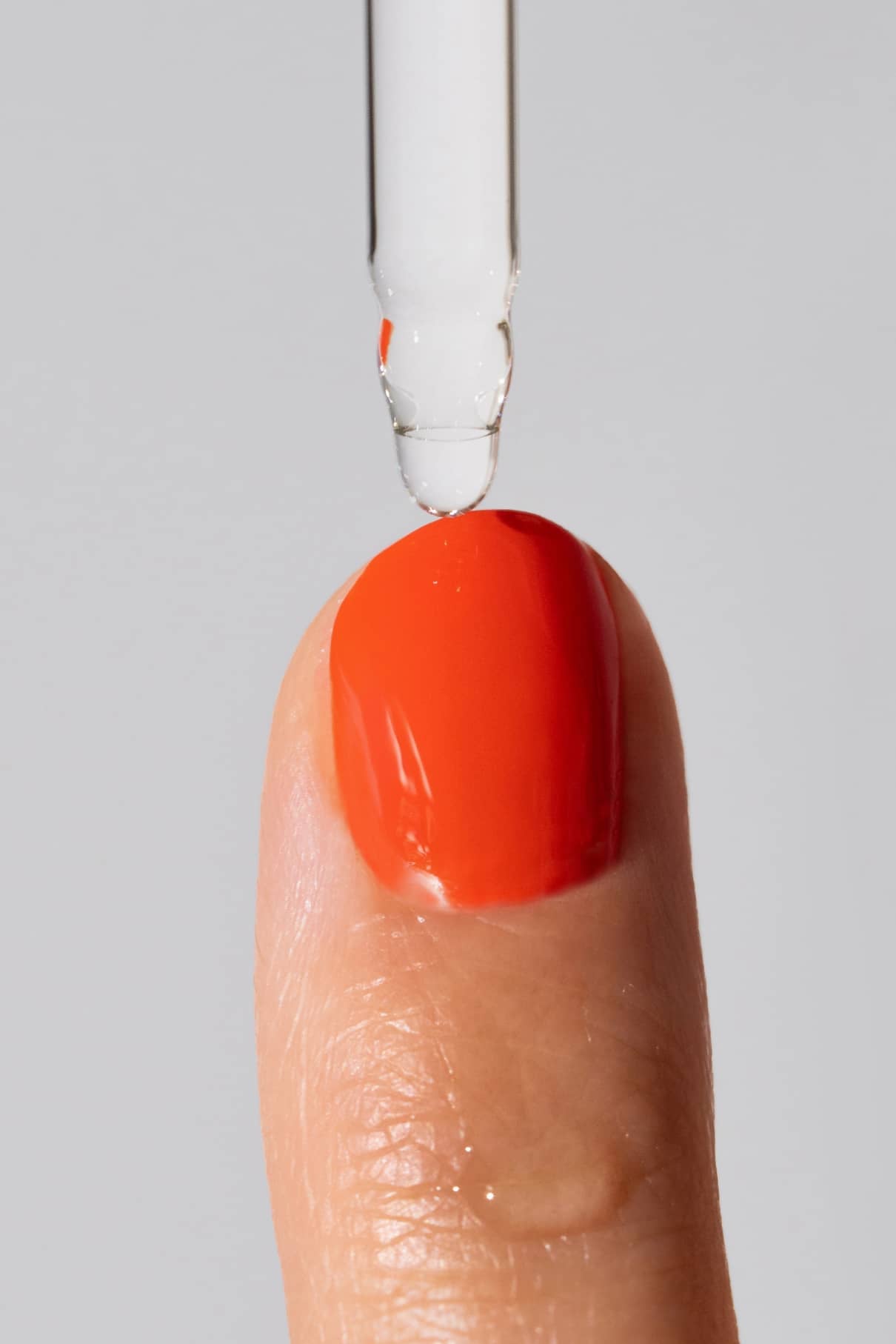 Ein Tropfer spendet Quick Dry Solution auf eine Fingerspitze mit leuchtend rotem Nagellack für schnelle Trocknung, damit Ihre Nagelfarbe schneller trocknet und glänzend bleibt.
