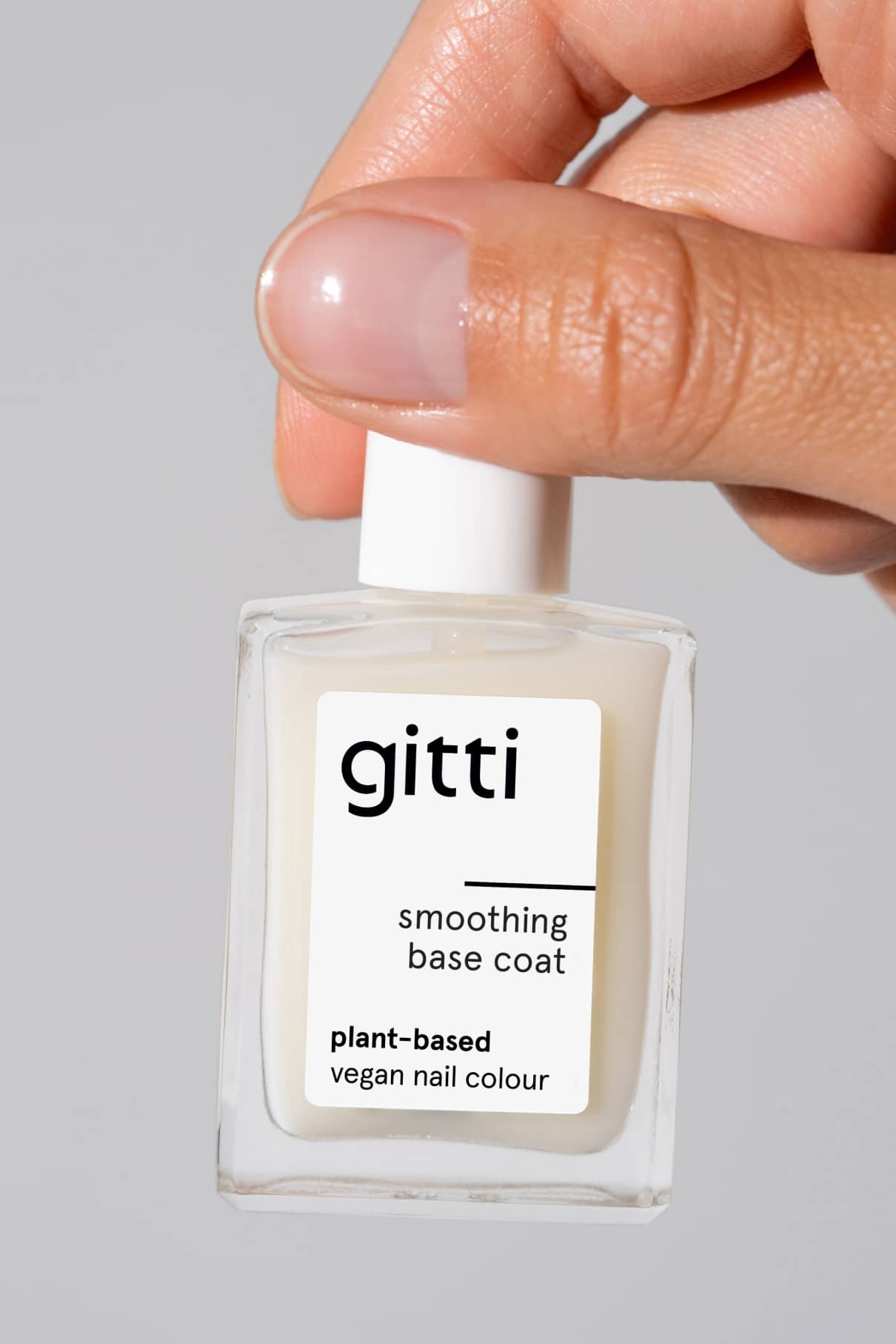 Eine Hand hält eine klare Flasche Smoothing Nail Primer, ein pflanzliches, veganes Nagelprodukt, ideal für Nagelpflege und Nägel glätten, um die Haftung der Farbe zu verbessern.
