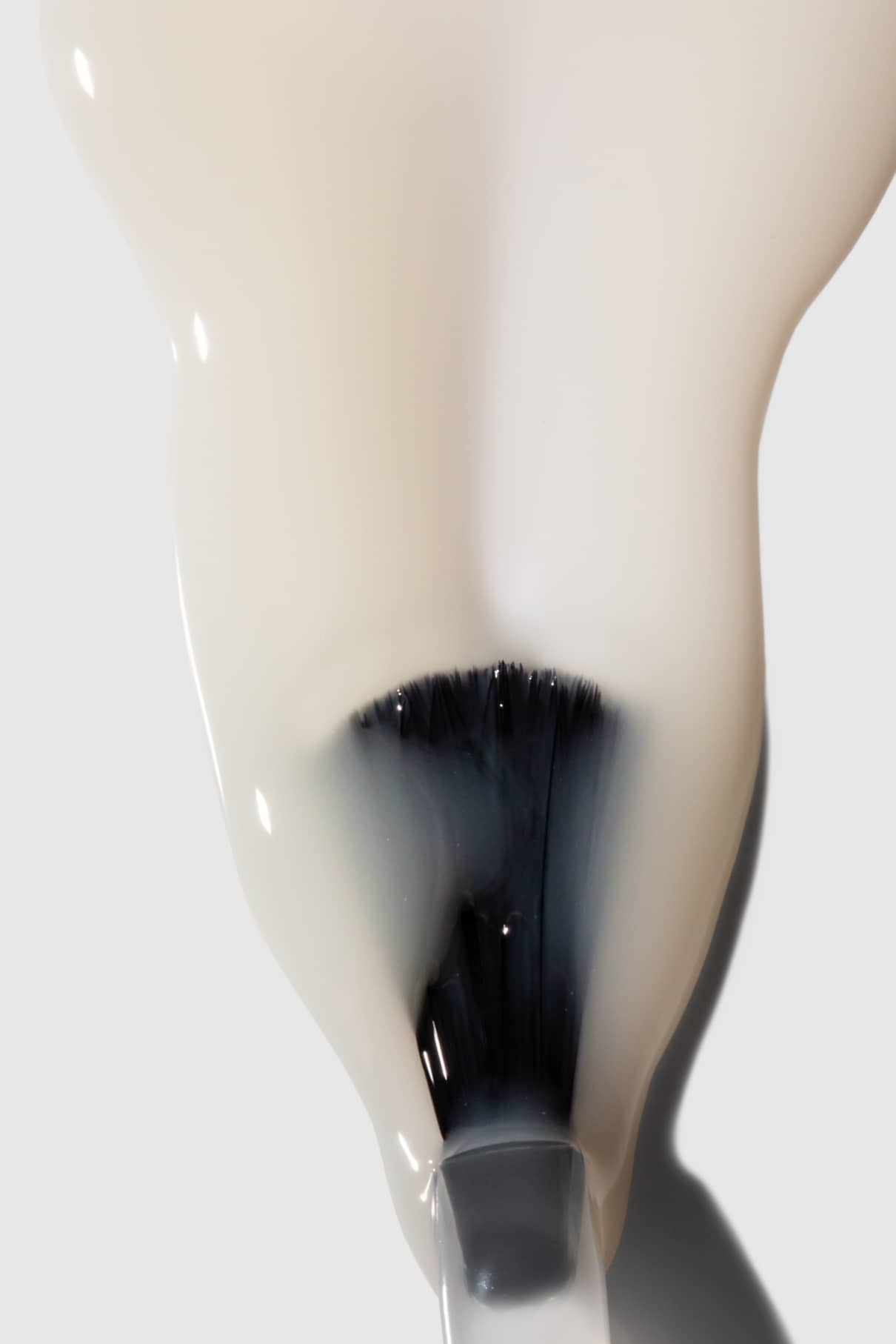 Nahaufnahme eines Nagellackpinsels beim Auftragen von Smoothing Nail Primer, einer milchig-weißen Schicht, die ideal zum Nägel glätten ist und für optimale Haftung der Farbe sorgt.