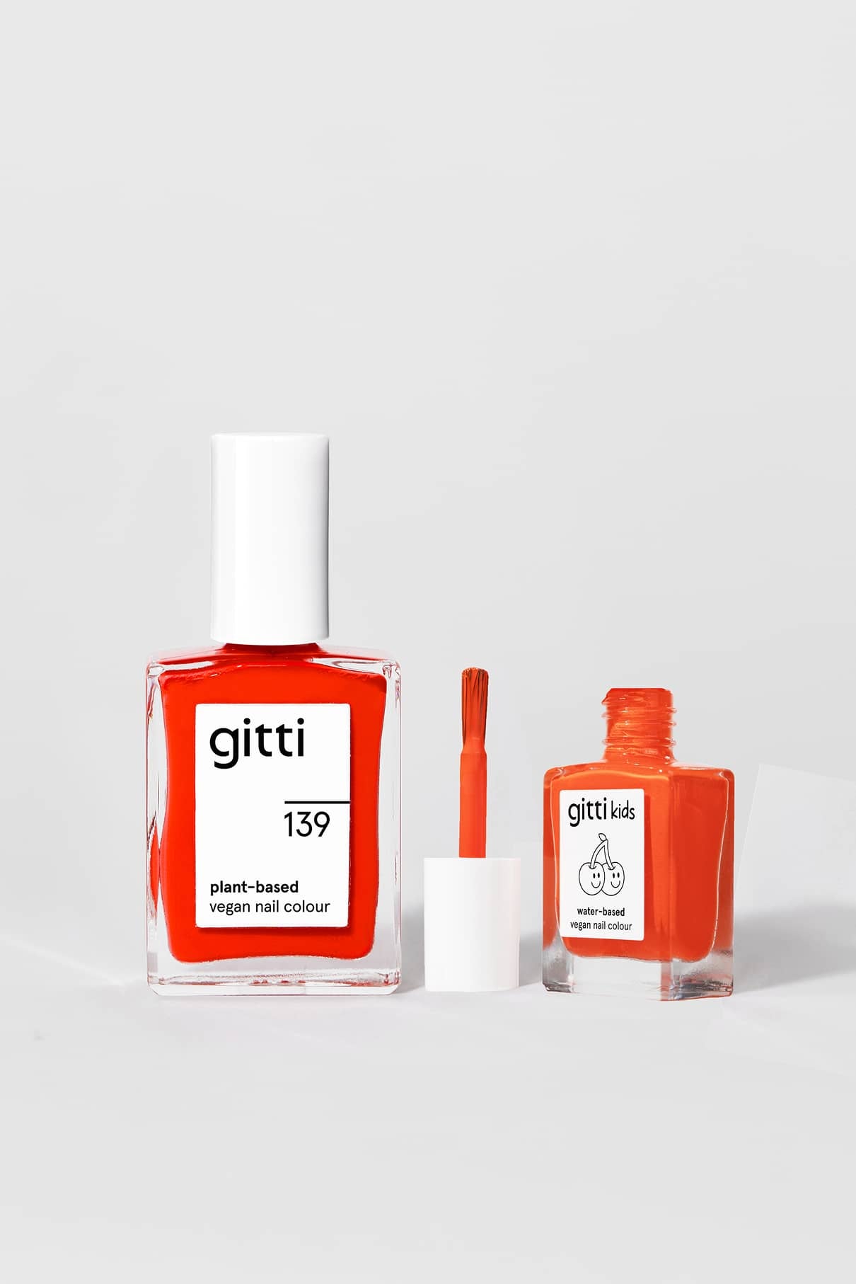 Zwei Flaschen mit orangefarbenem pflanzenbasiertem Nagellack aus dem Mini & Me Set sind auf weißem Hintergrund abgebildet: die größere ist mit gitti 139 beschriftet, die kleinere mit herausgezogenem Pinsel ist mit gitti kids beschriftet.