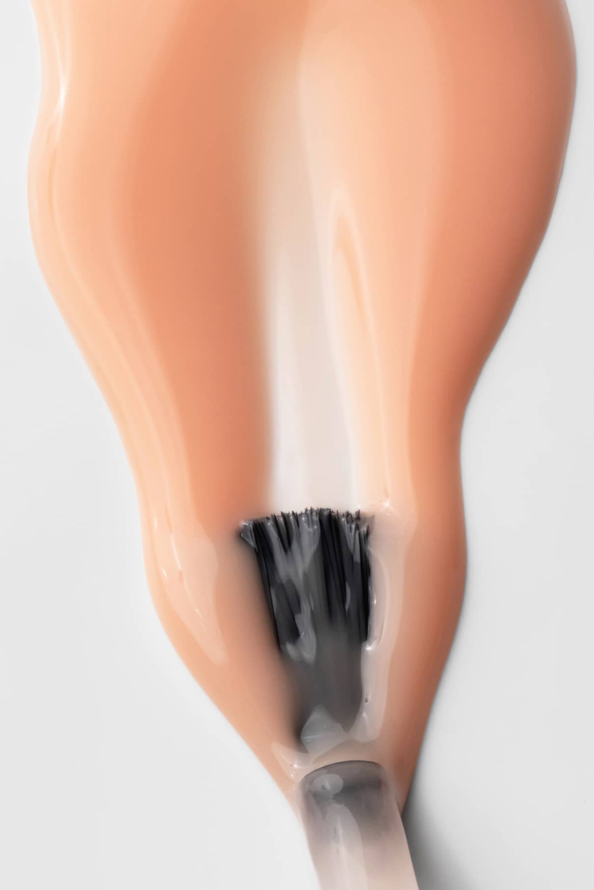 Nahaufnahme des gitti no. 002-Pinsel beim Auftragen einer Schicht nudefarbenen, von der Pantone-Farbe des Jahres 2024 inspirierten Nagellacks auf eine weiße Fläche.