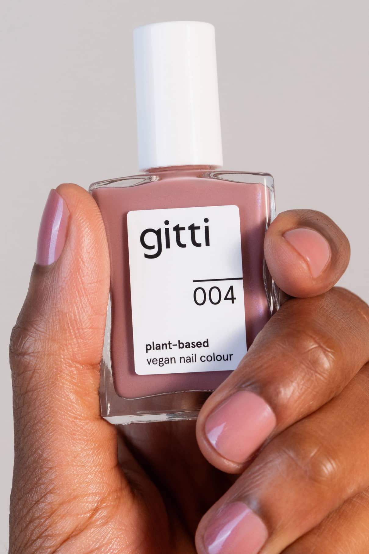 Eine Hand mit einer Flasche Colour Up Duo und passend lackierten Nägeln.