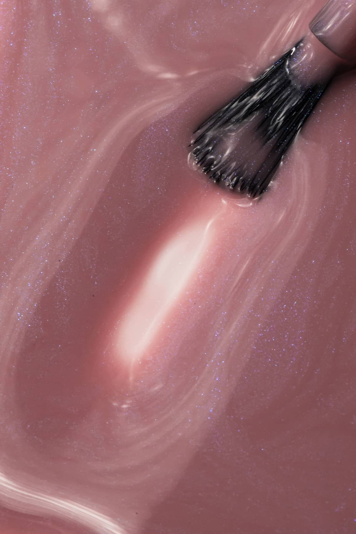 Nahaufnahme eines Pinsels, mit dem gitti no. 004, ein schimmernder rosa-mauvefarbener Nagellack mit sichtbaren Wirbelmustern und einer glänzenden Textur.