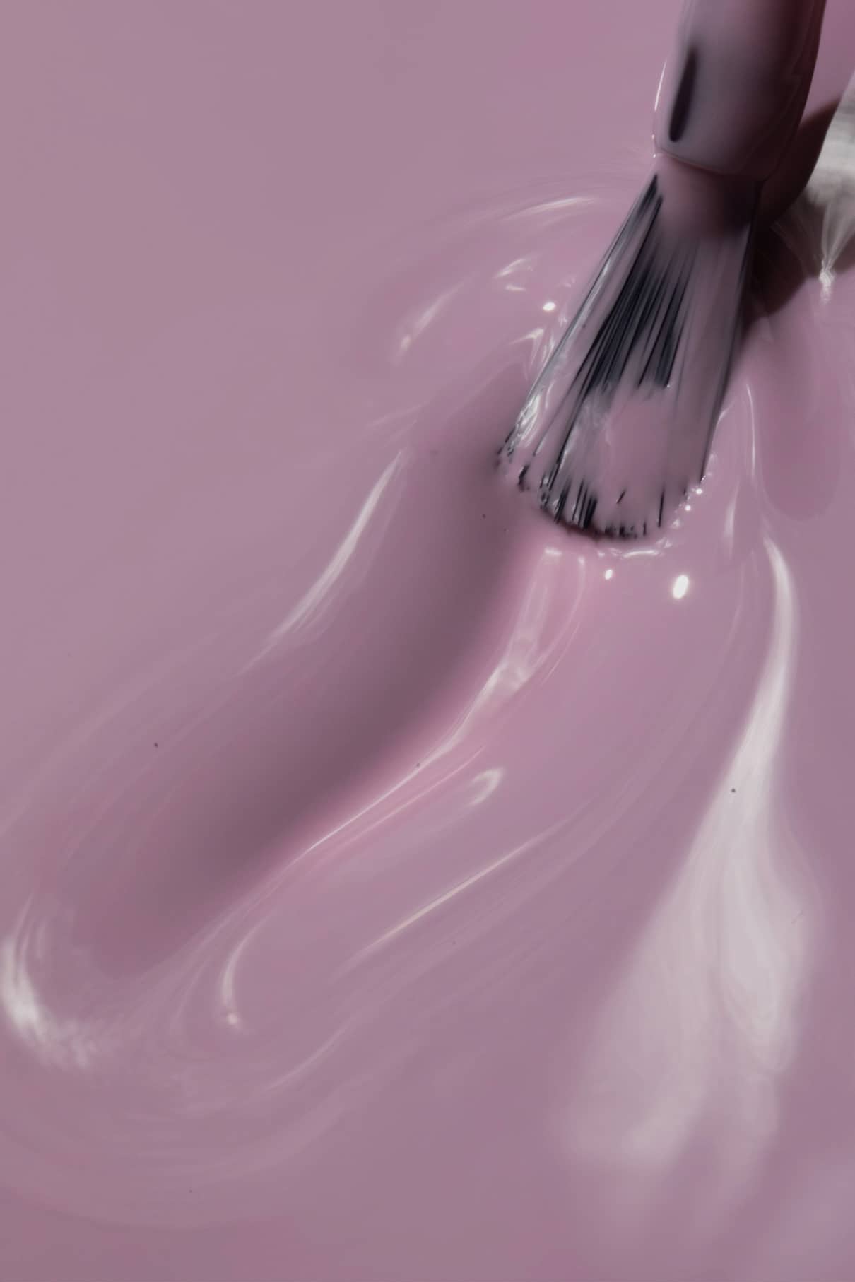 Eine Nahaufnahme von gitti no. 021 wird mit einem Pinsel aufgetragen und zeigt seinen glänzenden rosa Farbton, der durch kühles Lila akzentuiert wird und ein schickes, kühles Finish auf einer glatten Oberfläche erzeugt.