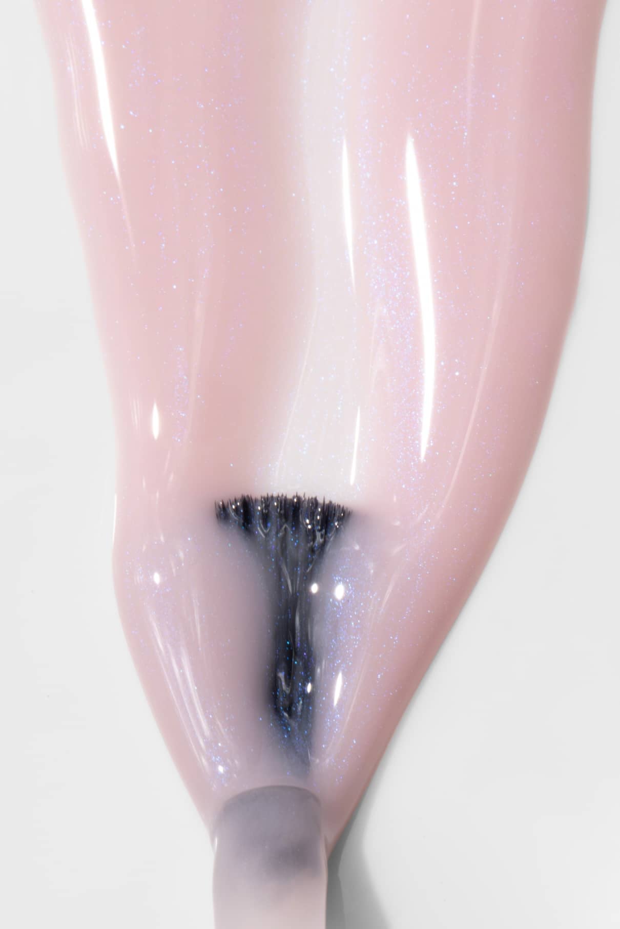 Nahaufnahme eines Pinsels, mit dem gitti no. 025, ein halbtransparenter rosa Nagellack mit bläulichem Schimmer, auf einen Fingernagel.