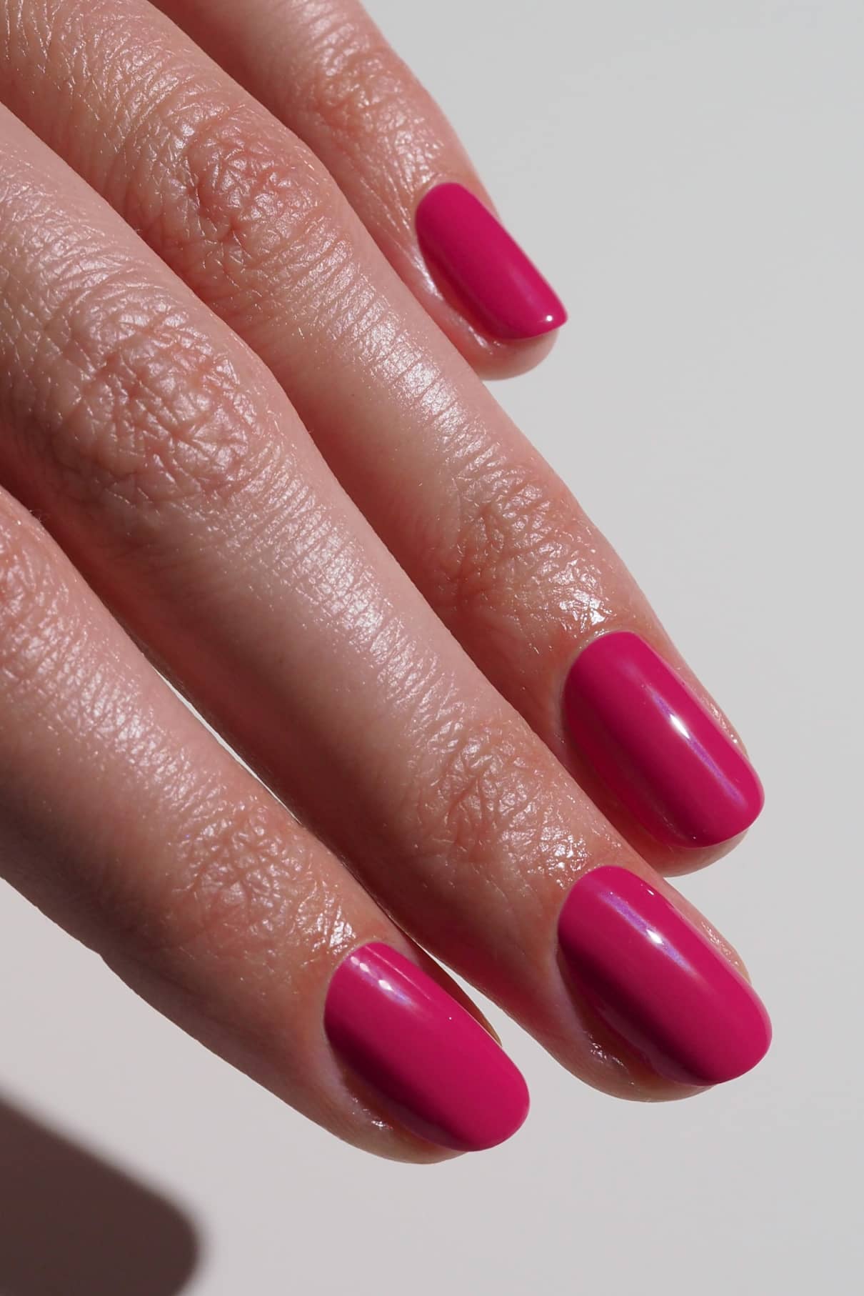 Nahaufnahme einer Hand mit sauber manikürten Nägeln, die in dem glänzenden, leuchtenden Fuchsia-Pink-Farbton gitti no. 027.